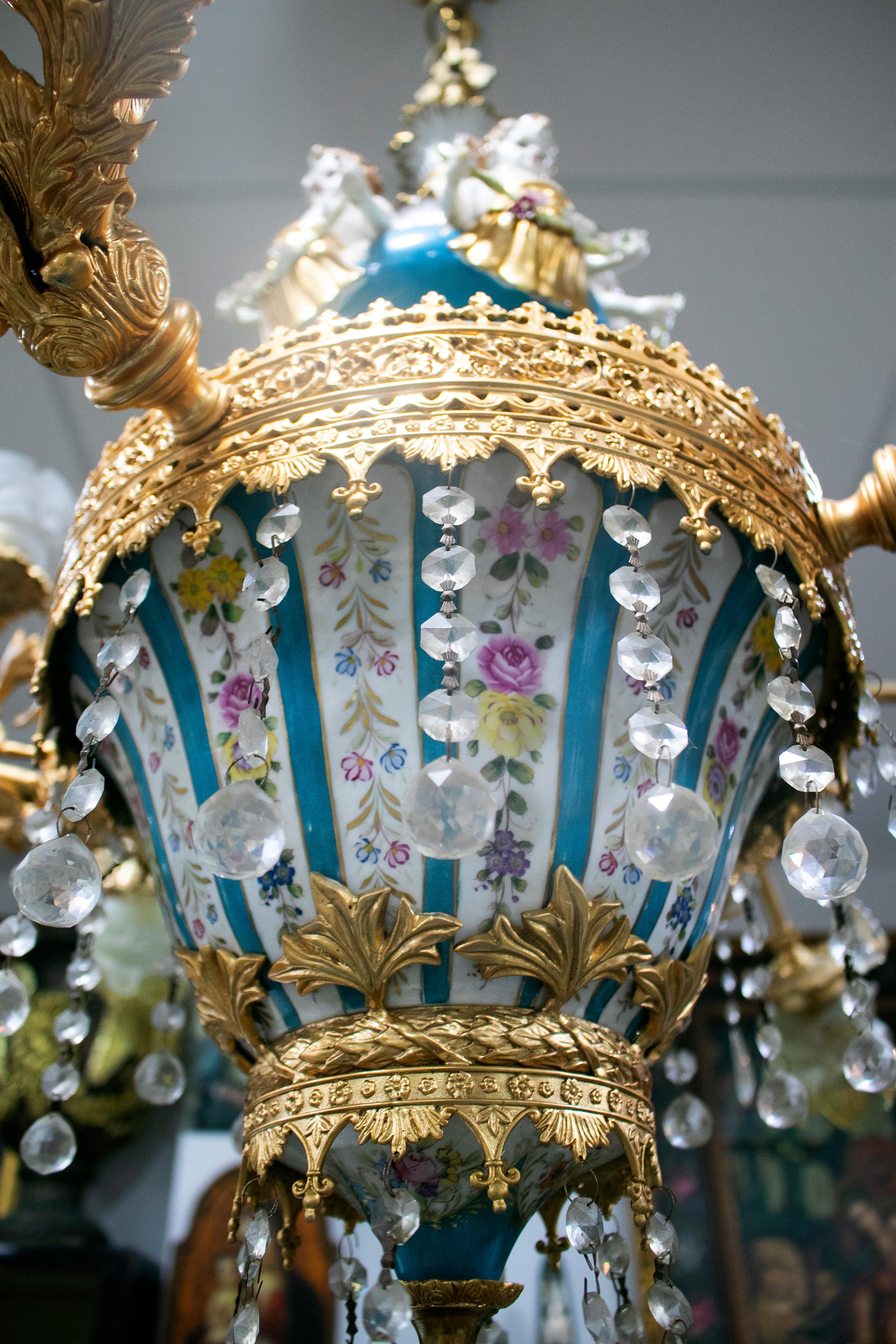 Ornate 1990s French white and blue hand painted porcelain chandelier with bronze arms and hanging glass ornaments.

 