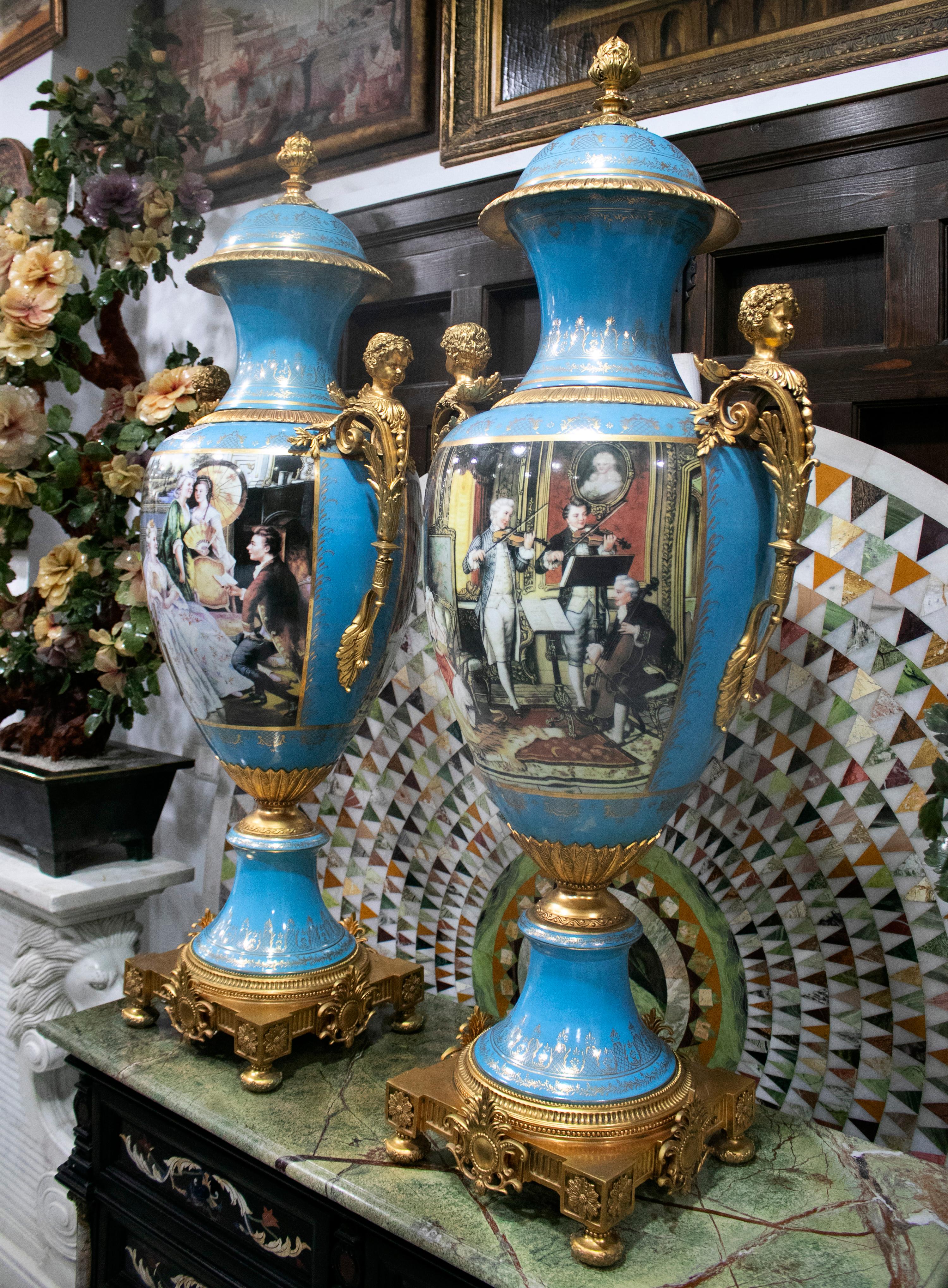 1990s French pair of blue hand painted white porcelain vases with scenes and large bronze handles with cherubs.

 