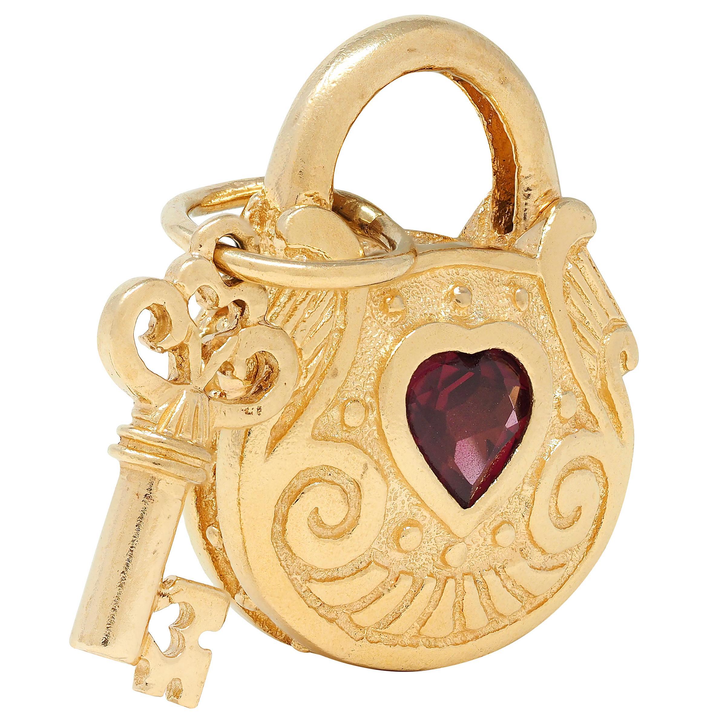 Designed as a highly fully dimensional padlock with scrolling skeleton key charm
Accented by grooved scroll motif throughout with pierced heart motif on key
Centering a flush set heart cut garnet measuring 5.0 x 5.0 mm
Transparent medium purplish