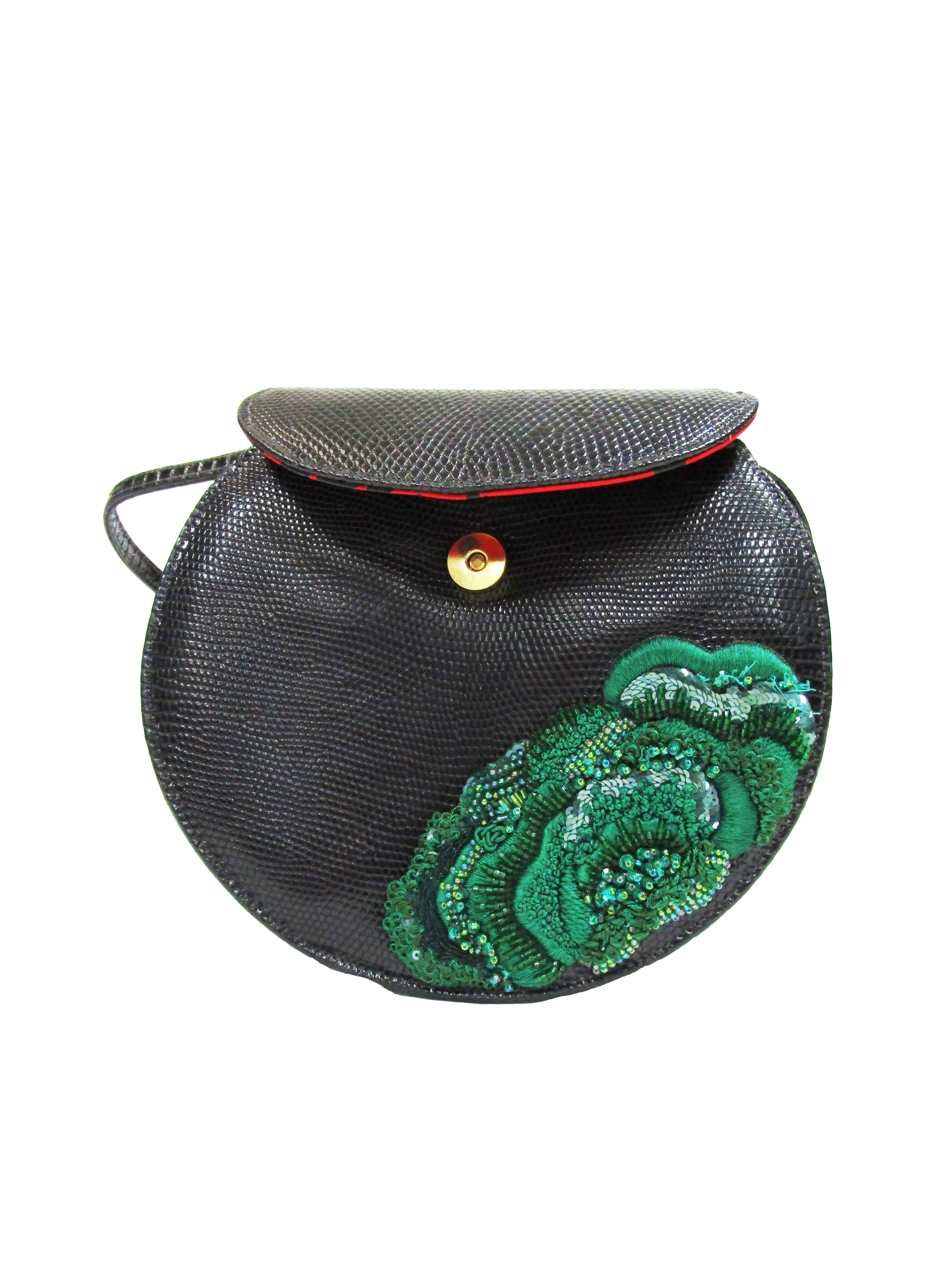 
Spectacularly designed black lizard bag by Geoffrey Beene New York! This evening bag features black lizard with a meticulously embroidered and beaded green flower. The strap lays comfortably across the shoulder and the purse falls right on the hip.