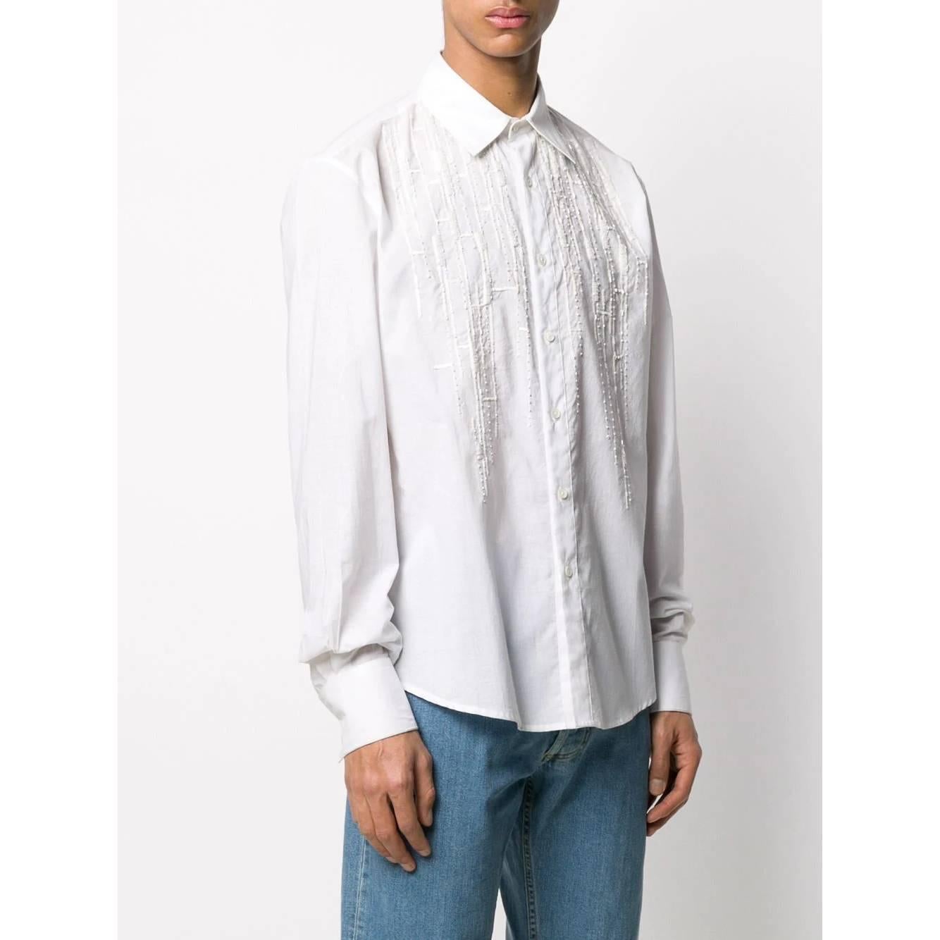 Gianfranco Ferré optic white cotton shirt. It features a straight fit, a classic collar, sequins and beads embroideries on the chest, long sleeves, buttoned cuffs, a front button fastening and a curved hemline.

The item shows some missing sequins,
