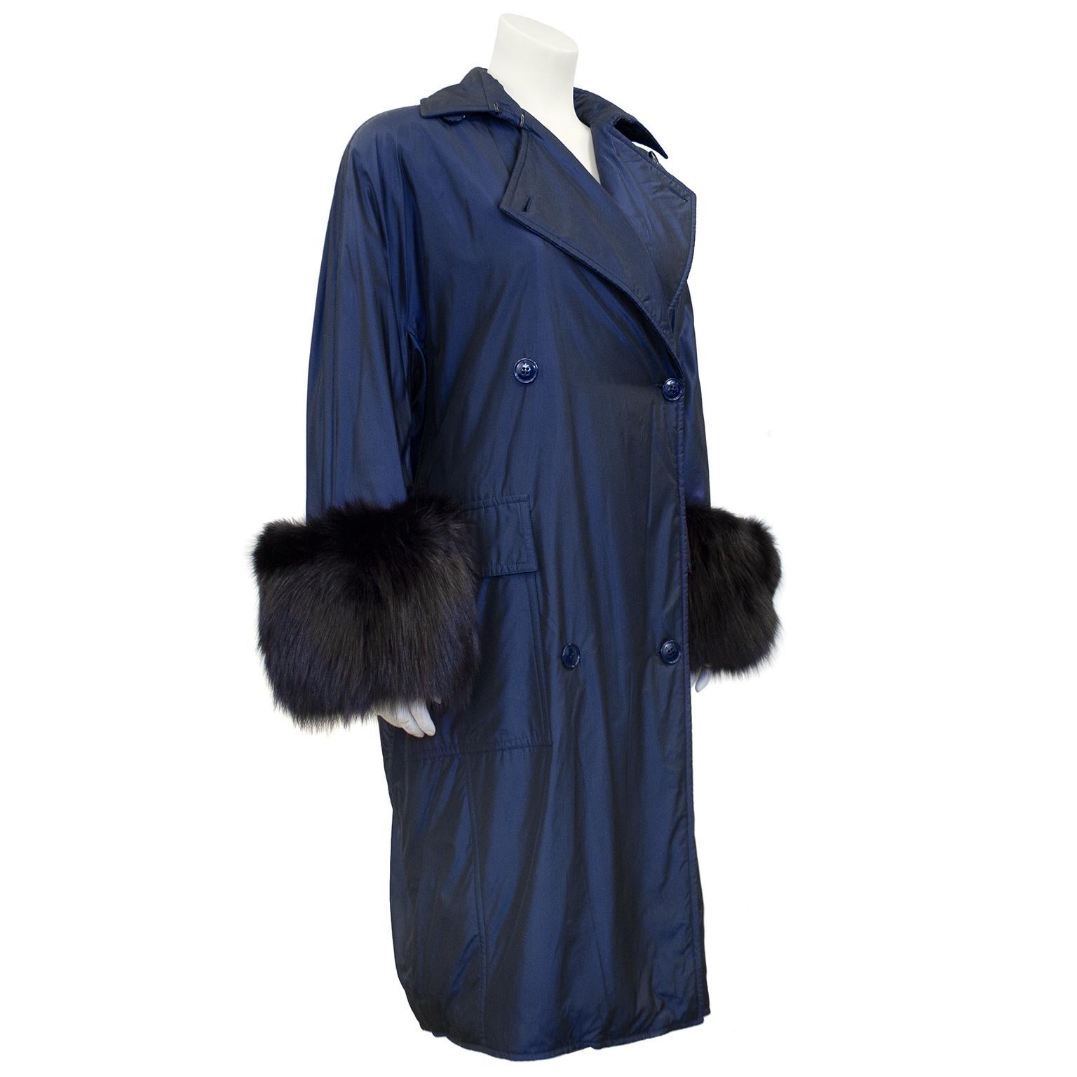 1990s Gianfranco Ferre iridescent navy blue trench coat with black oversized black fox fur cuffs. Double breasted with a notched collar and wide lapels and oversized storm pockets. Single back vent and quilted lining. Excellent vintage condition.