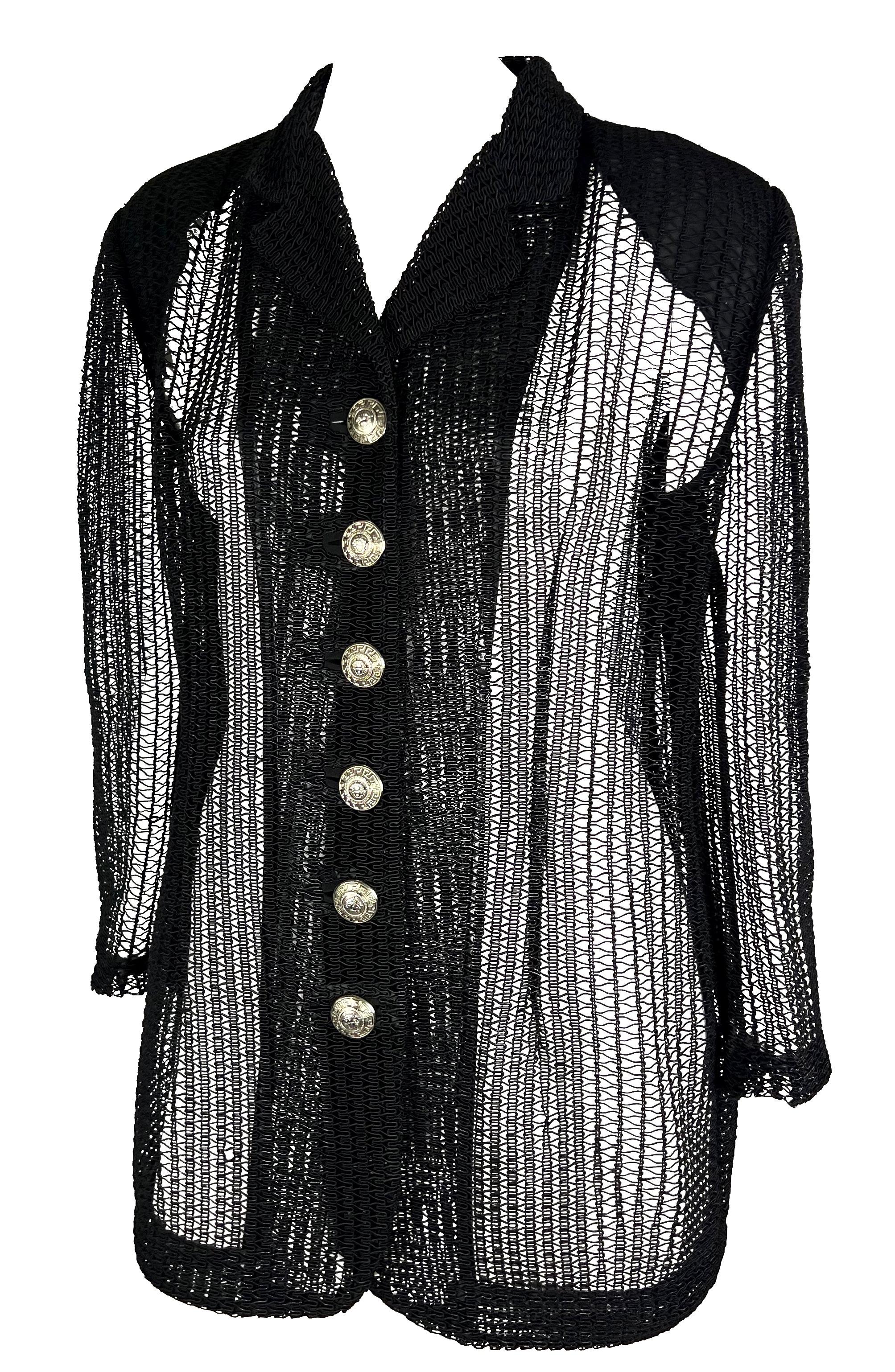 Presenting a black knit Gianni Versace sheer blazer, designed by Gianni Versce. From the 1990s, this loose-knit blazer effortlessly combines sophistication and comfort. The oversized silhouette adds a contemporary edge, while the large silver-tone