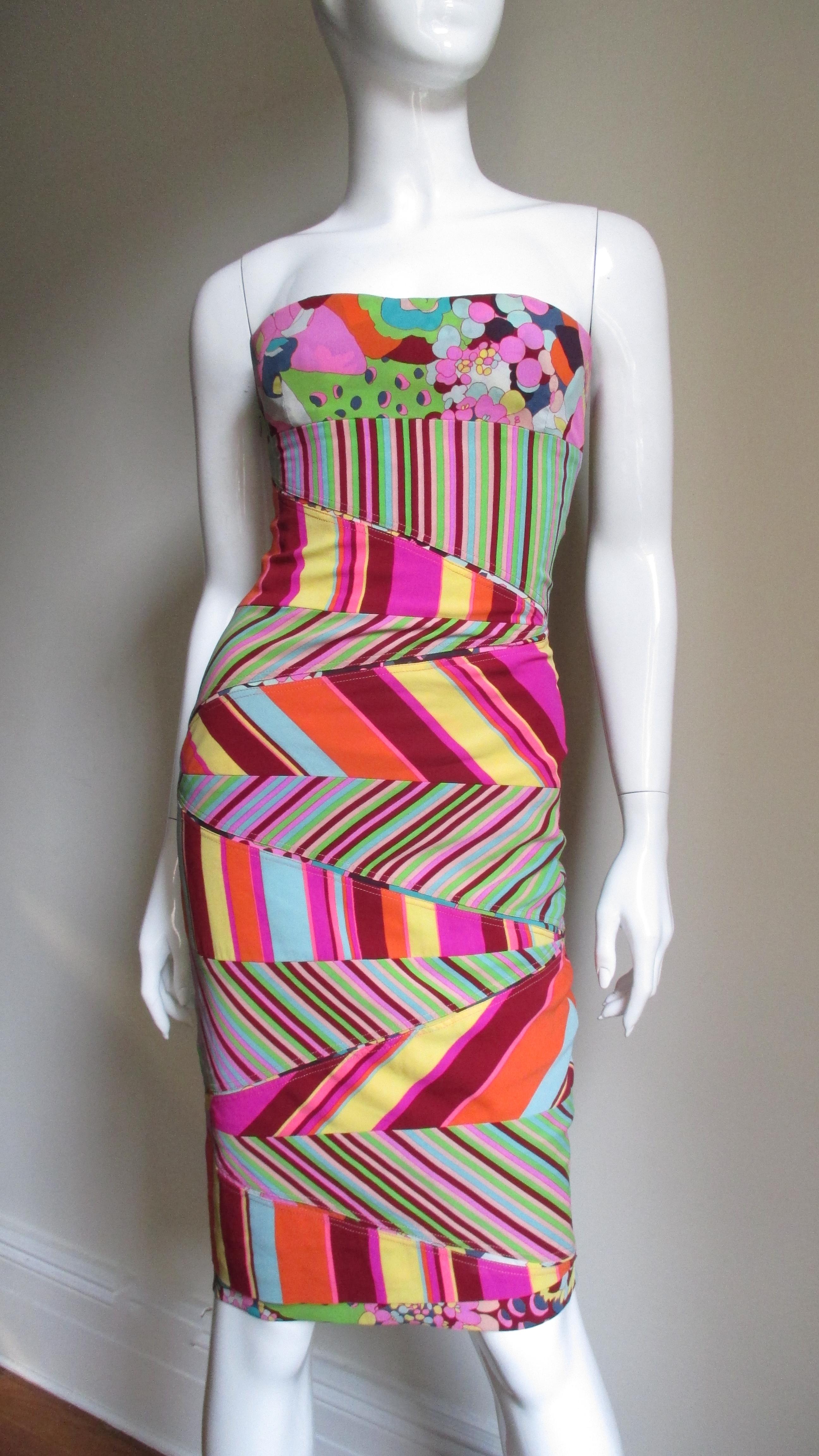 A fitted body conscious silk jersey bustier dress from Gianni Versace Couture.  It is comprised of a clever combination of colorful varied striped shaped angular panels. A portion of the bust and a thin band at the hem consists of an abstract flower