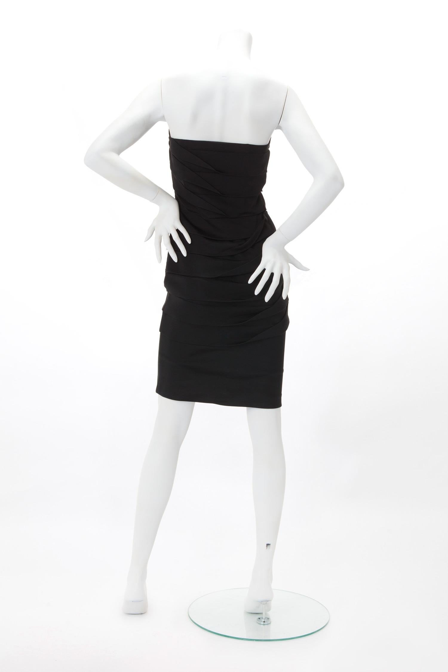 Vestido negro plisado sin tirantes Gianni Versace Couture de los años 90.

Corpiño sin tirantes en mezcla de seda con panel interior crema; pliegues asimétricos en cascada desde el corpiño imperio. Cremallera oculta en la costura lateral.

Se ajusta
