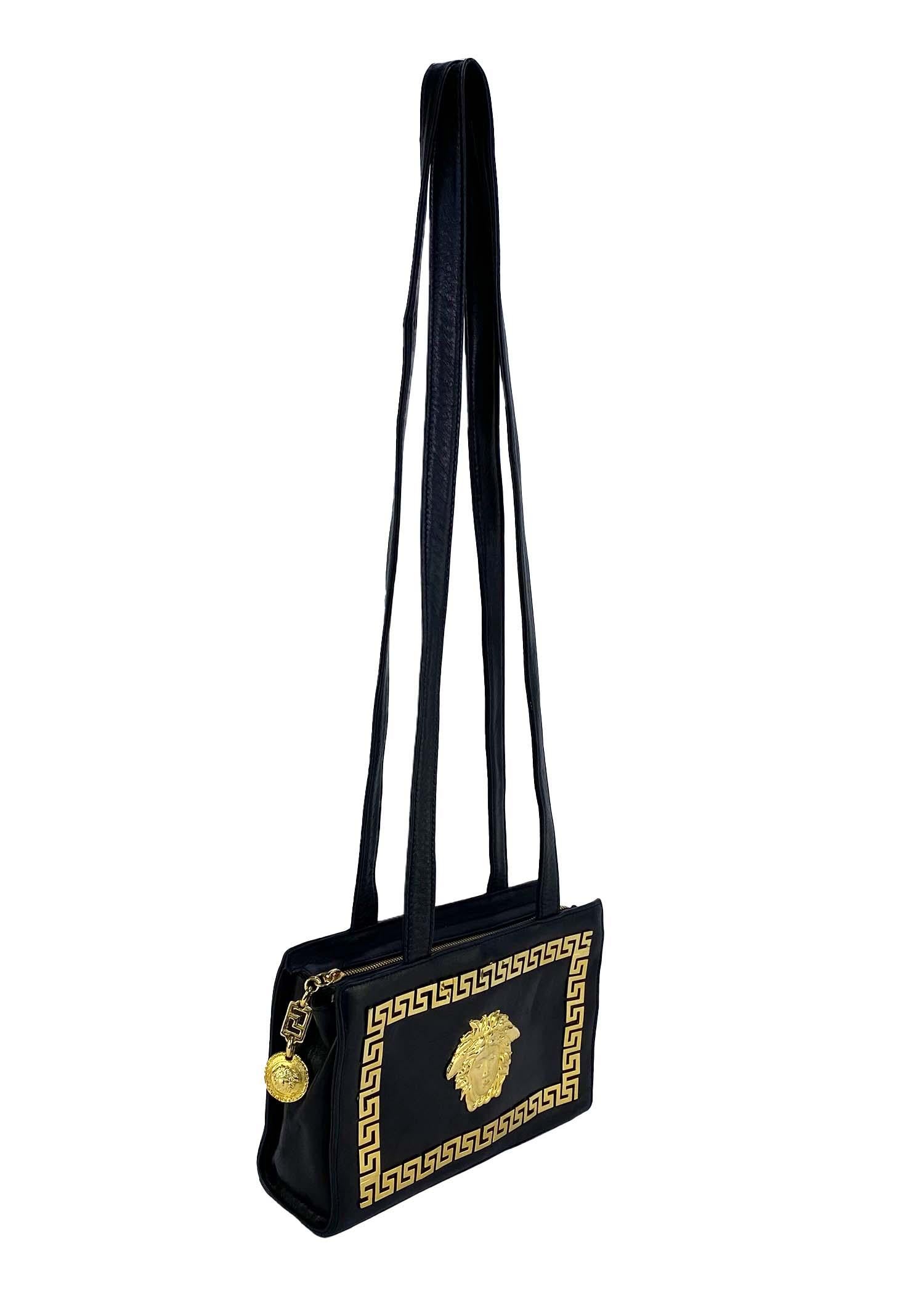 Presenting a classically Gianni Versace Couture purse, designed by Gianni Versace. Created in the early/mid 1990s, this bag constructed entirely of black leather proudly features a large gold Medusa logo with a Greek key border. Versatile, this bag