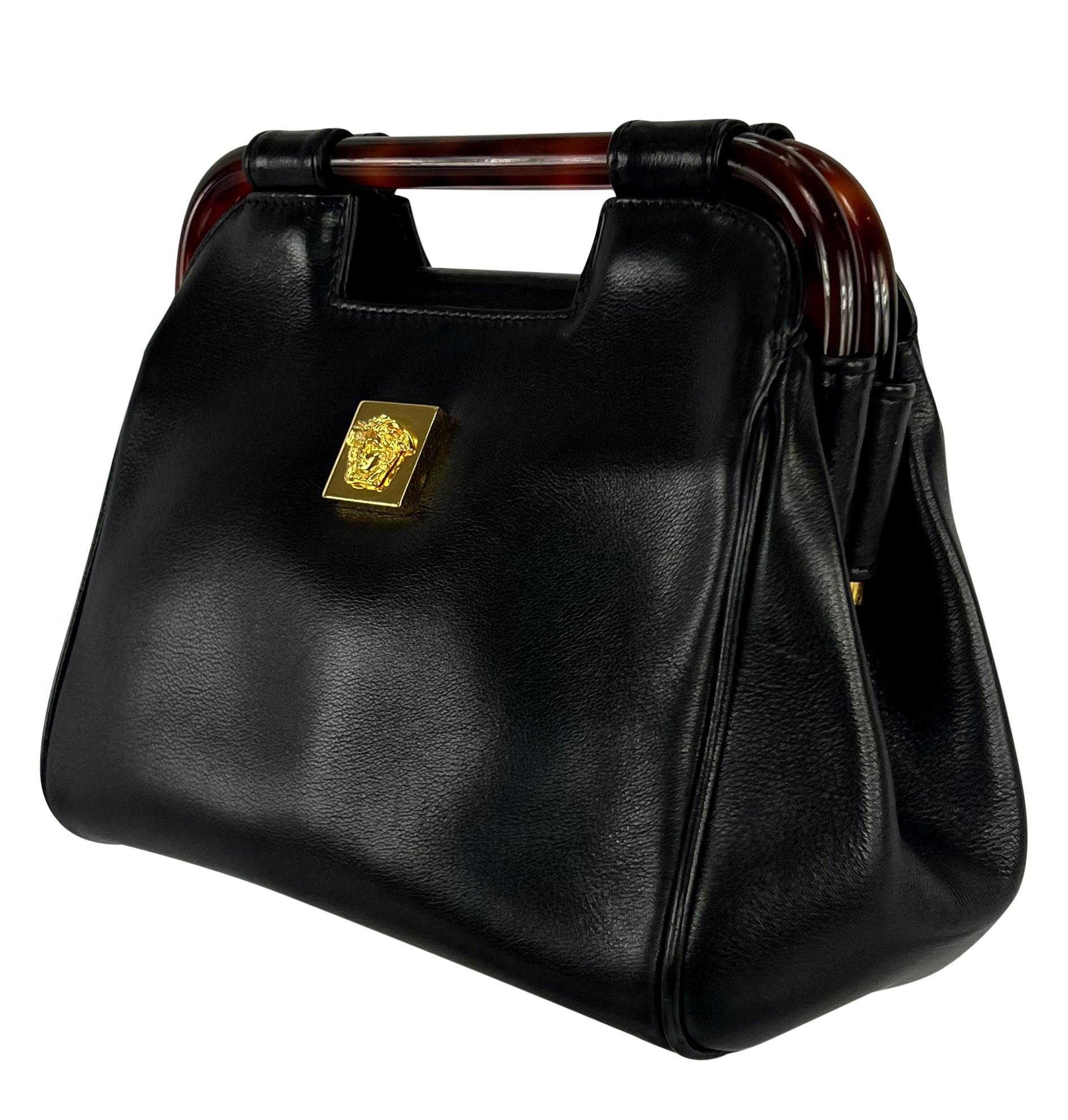 In the 1990s, Gianni Versace designed this unique top-handle bag for his namesake brand. This small black leather bag features a gold-tone Medusa emblem on the front and is complete with a faux tortoiseshell handle. 

Approximate