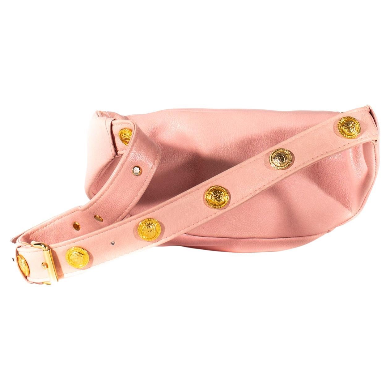 Presentamos Fabricado en suave piel rosa claro, este bolso de cintura vintage Gianni Versace grita Versace. Adornada con monedas doradas de Medusa, esta riñonera es perfecta para elevar cualquier atuendo. Este bolso se puede llevar de varias formas