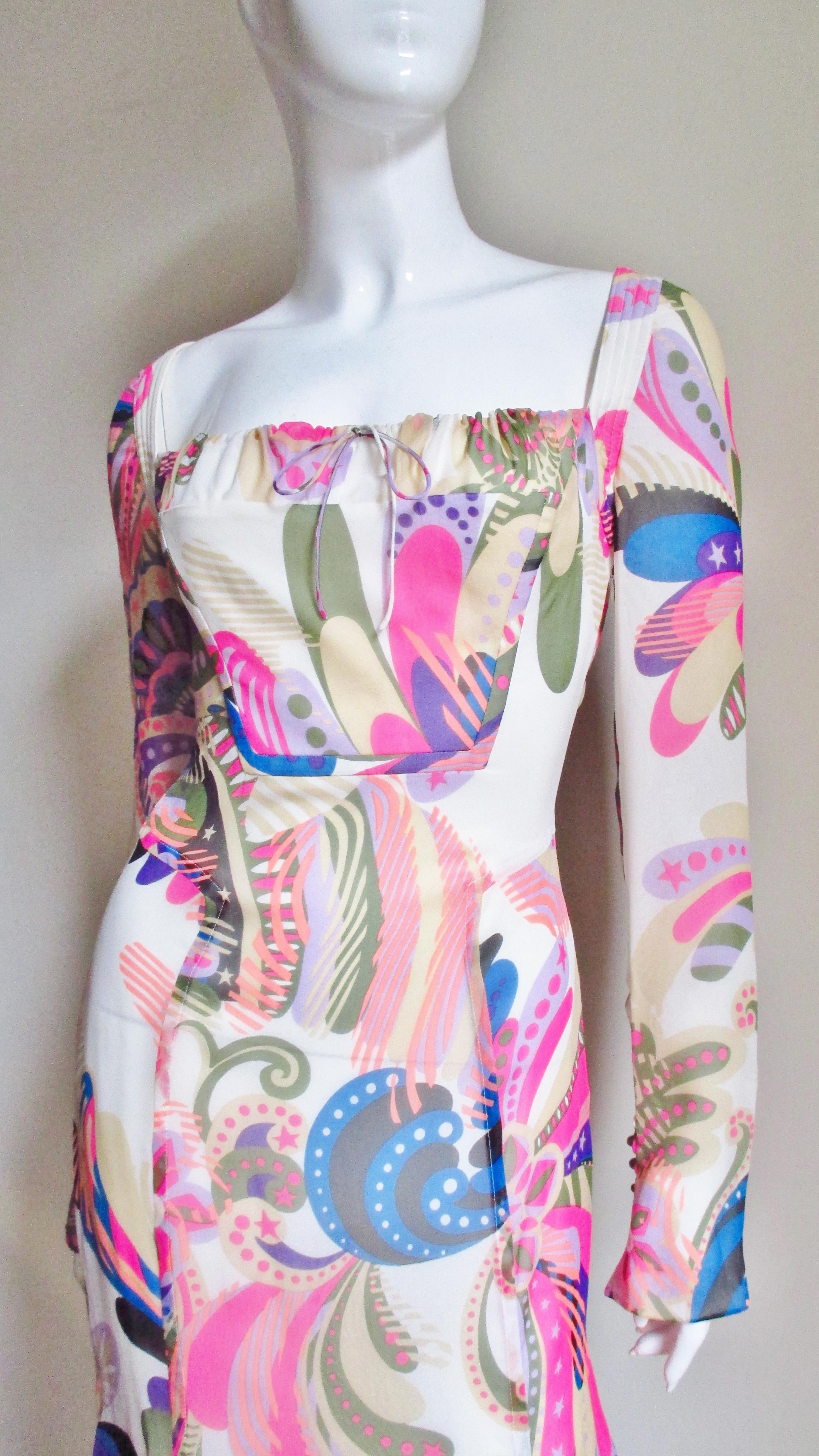 A beautiful silk dress from Gianni Versace Couture in a colorful pink, lavender and blue abstract print on a white background. The bodice has a front adjustable drawstring square neckline and the straight sleeves have 3 metal Versace stamped buttons