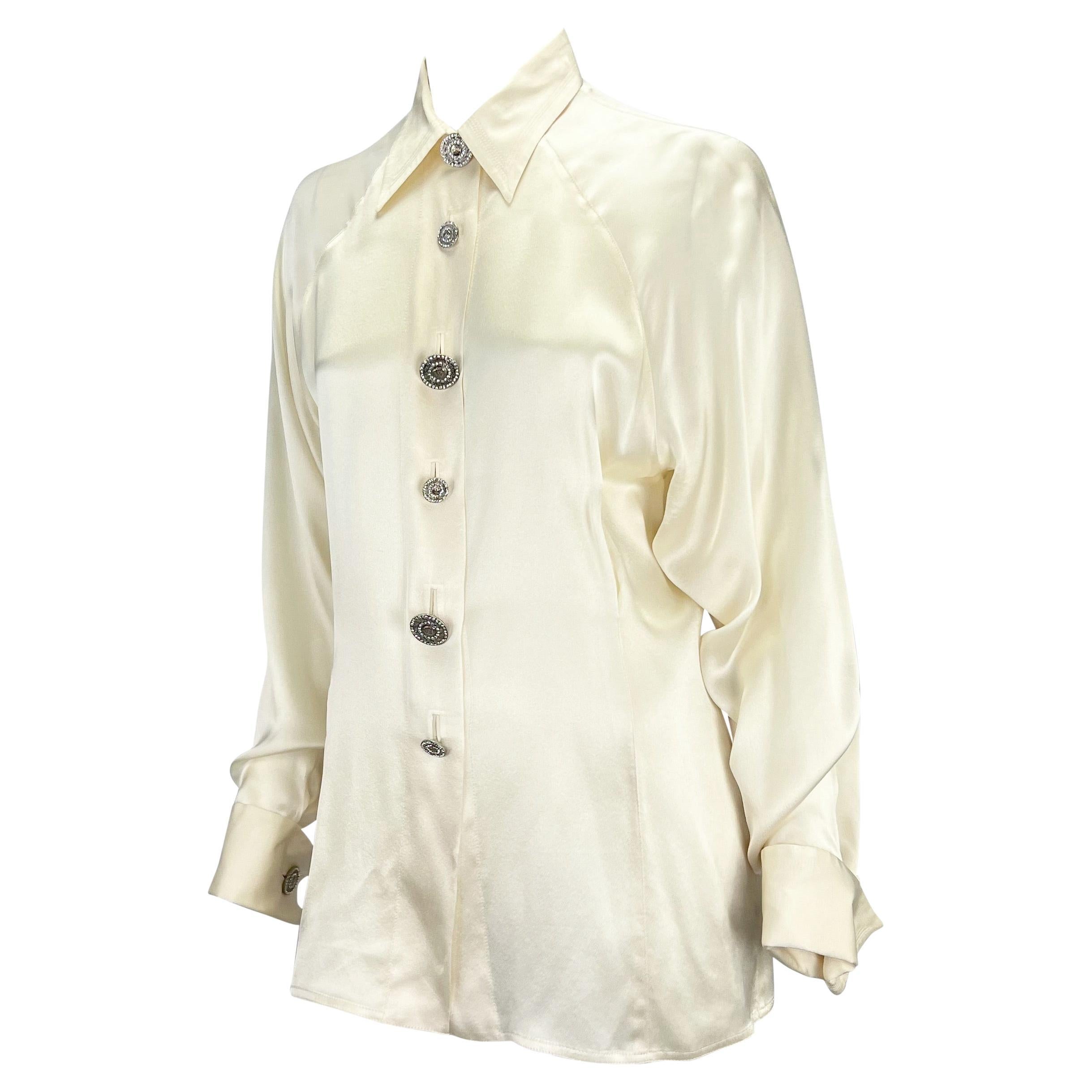 Presenting a creme silk satin Gianni Versace Couture blouse, designed by Gianni Versace. From the 1990s, this shirt is constructed entirely of luxurious silk that glistens with each movement. This top is made complete with rhinestone Versace Medusa