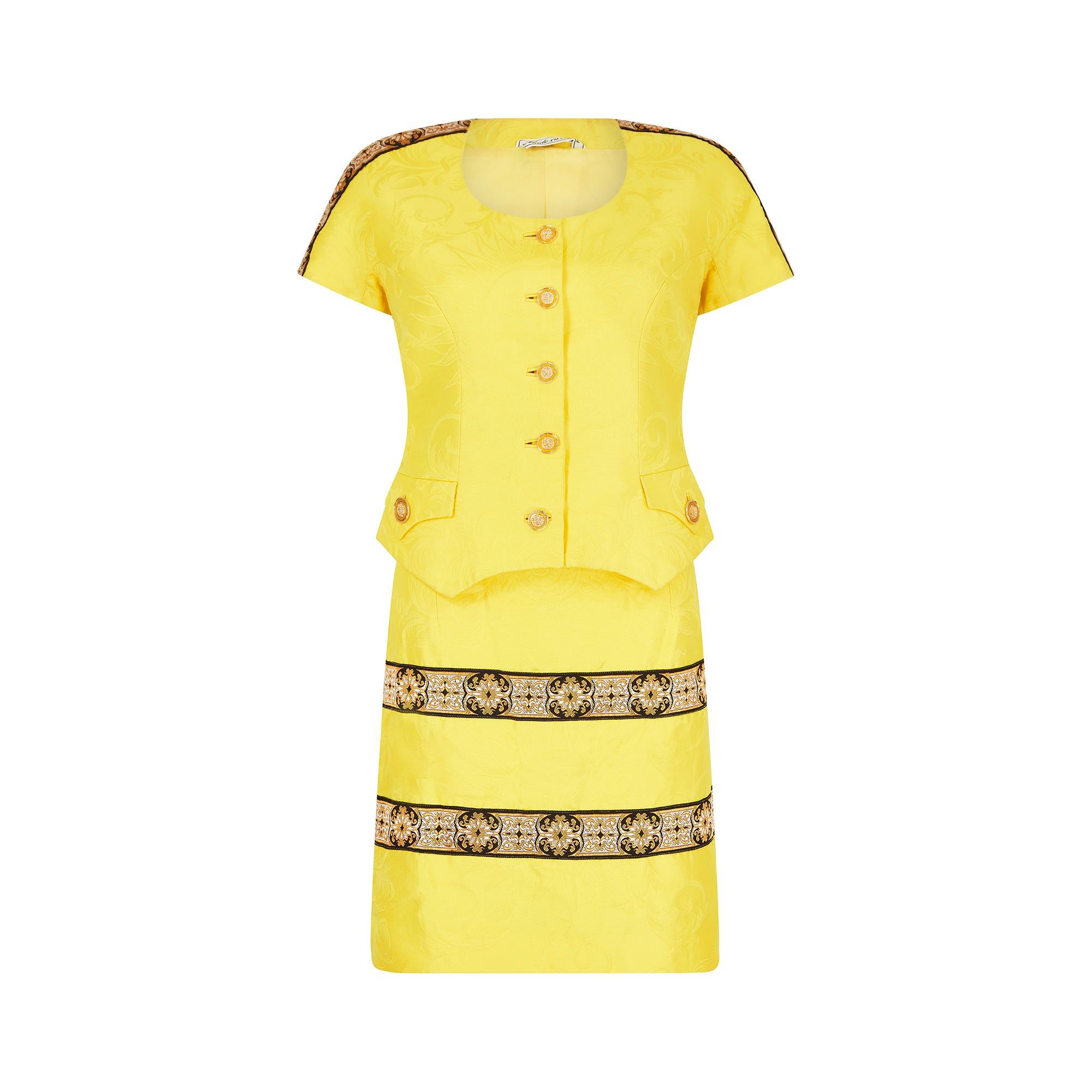 This 1990s baroque trim, celestial embossed suit in sunshine yellow is unquestionably the work of Gianni Versace and hails from arguably the pinnacle of his design genius; circa 1991 - 1995. 

The blended jacquard fabric features a giant sun with