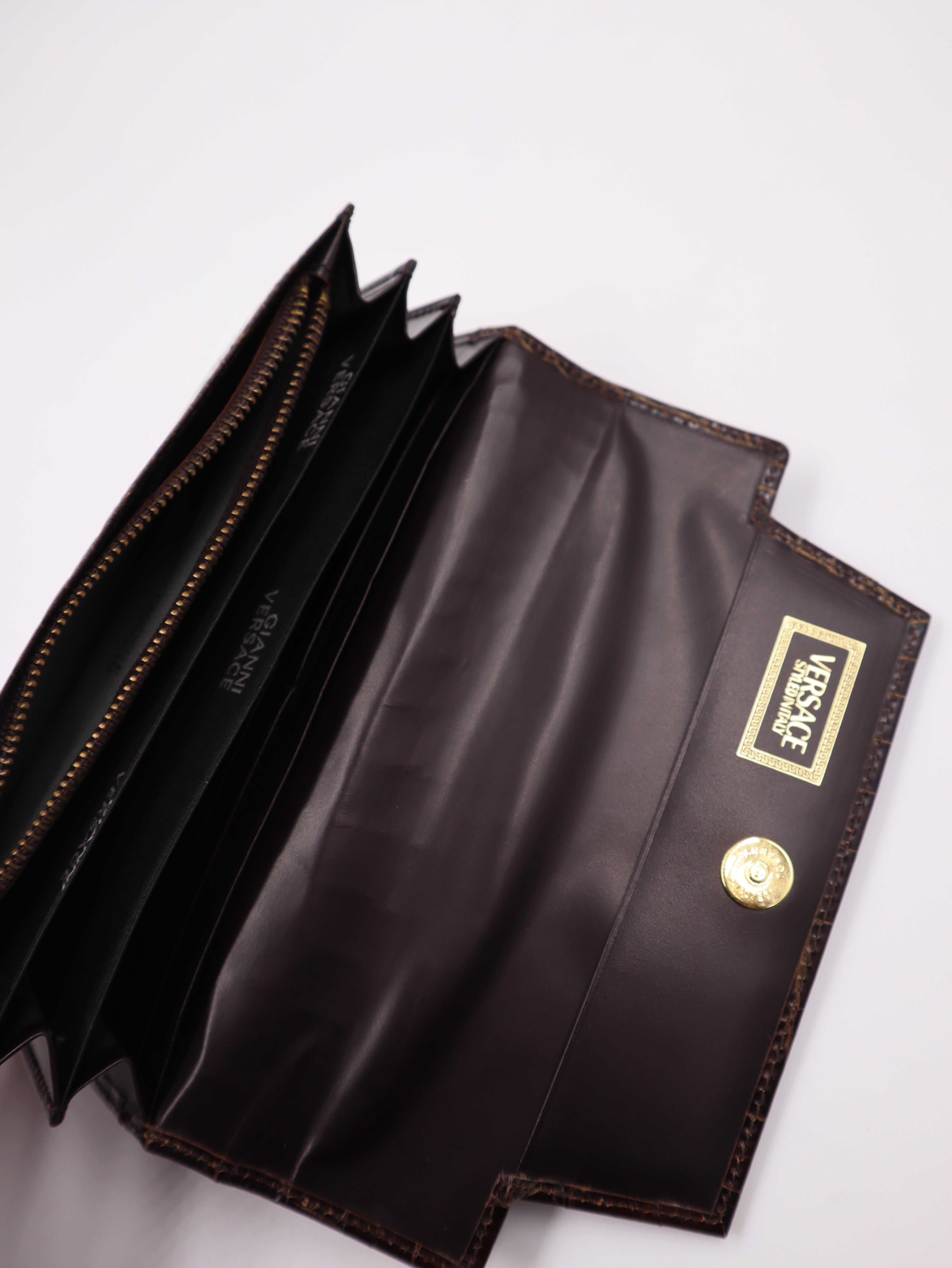 Pochette de collection en cuir croco Gianni Versace, avec des éléments de quincaillerie sunburst et un cuir croco marron. Elle comporte de nombreux emplacements pour cartes et un compartiment séparé pour les notes, le téléphone portable et plus