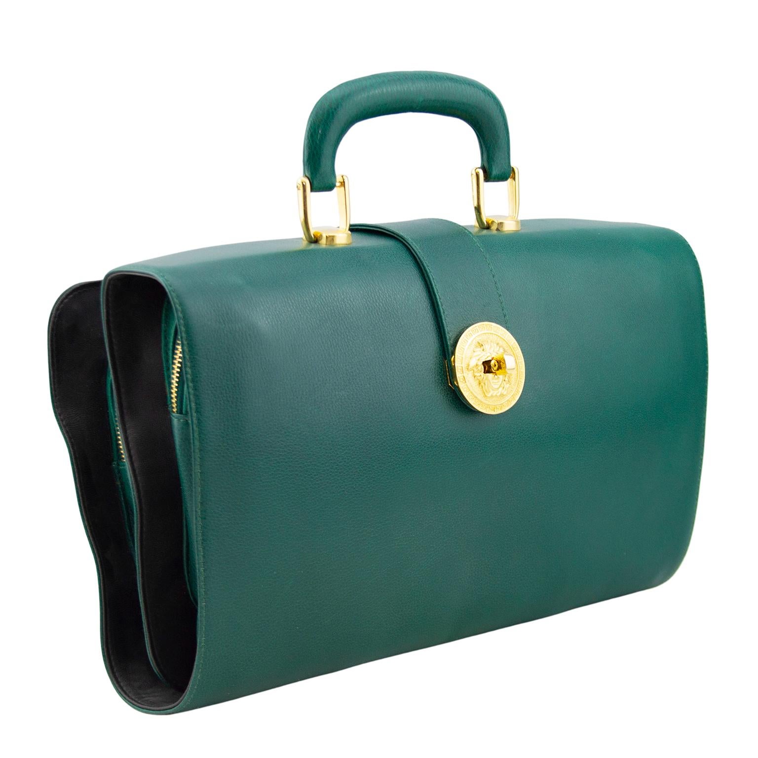 Very unique Versace dark green leather folding travel bag from the 1990s. Single top handle and gold tone hardware with large round Medusa twist lock closure. Bag unfolds revealing many pockets of varying size for packing everything you need from