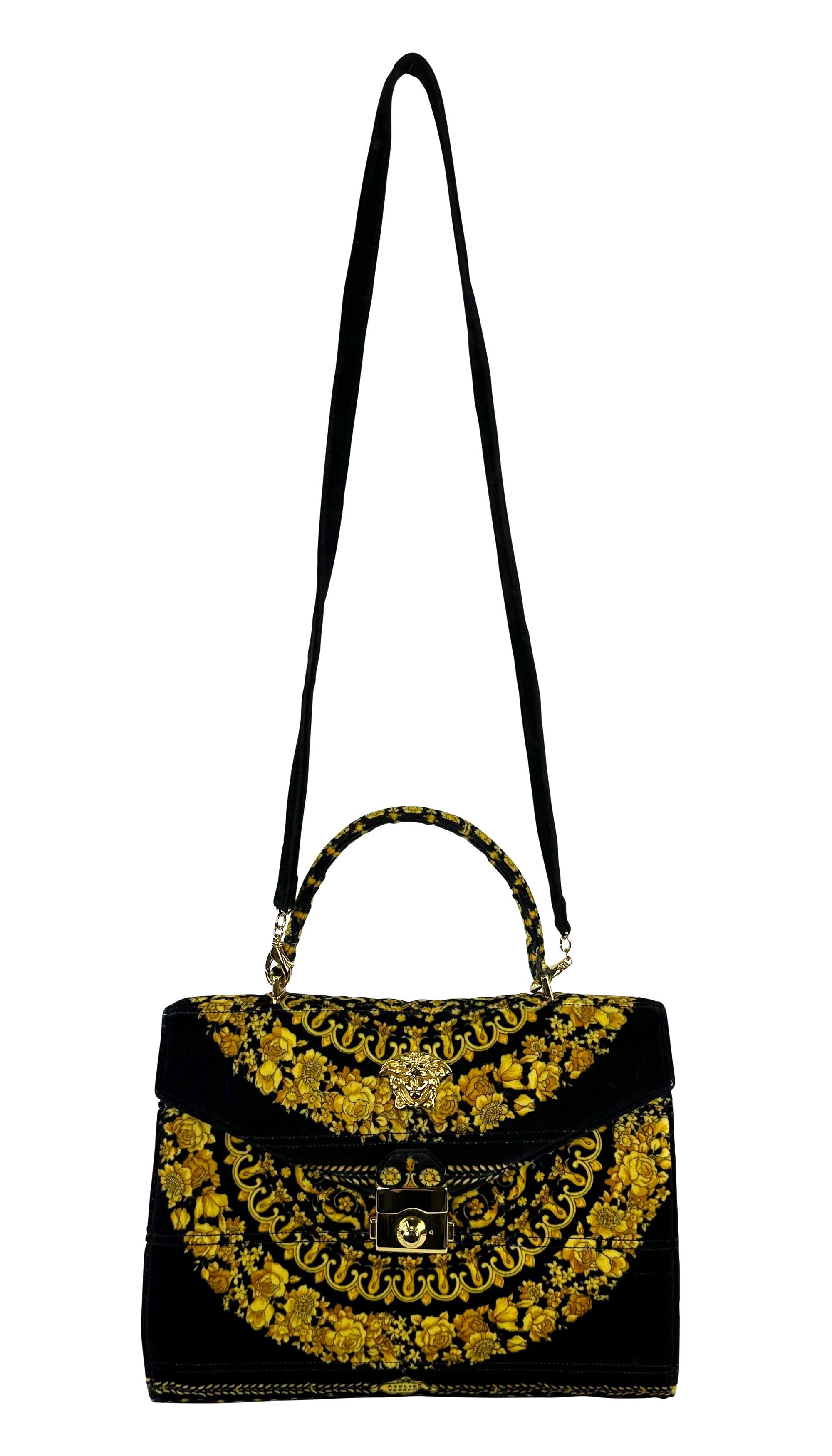 This black and gold Gianni Versace top handle bag is made entirely of velvet and features one of the brand's signature Atelier Versace baroque prints. The flap-style bag is adorned with a large gold Versace Medusa accent at the front and a pinch