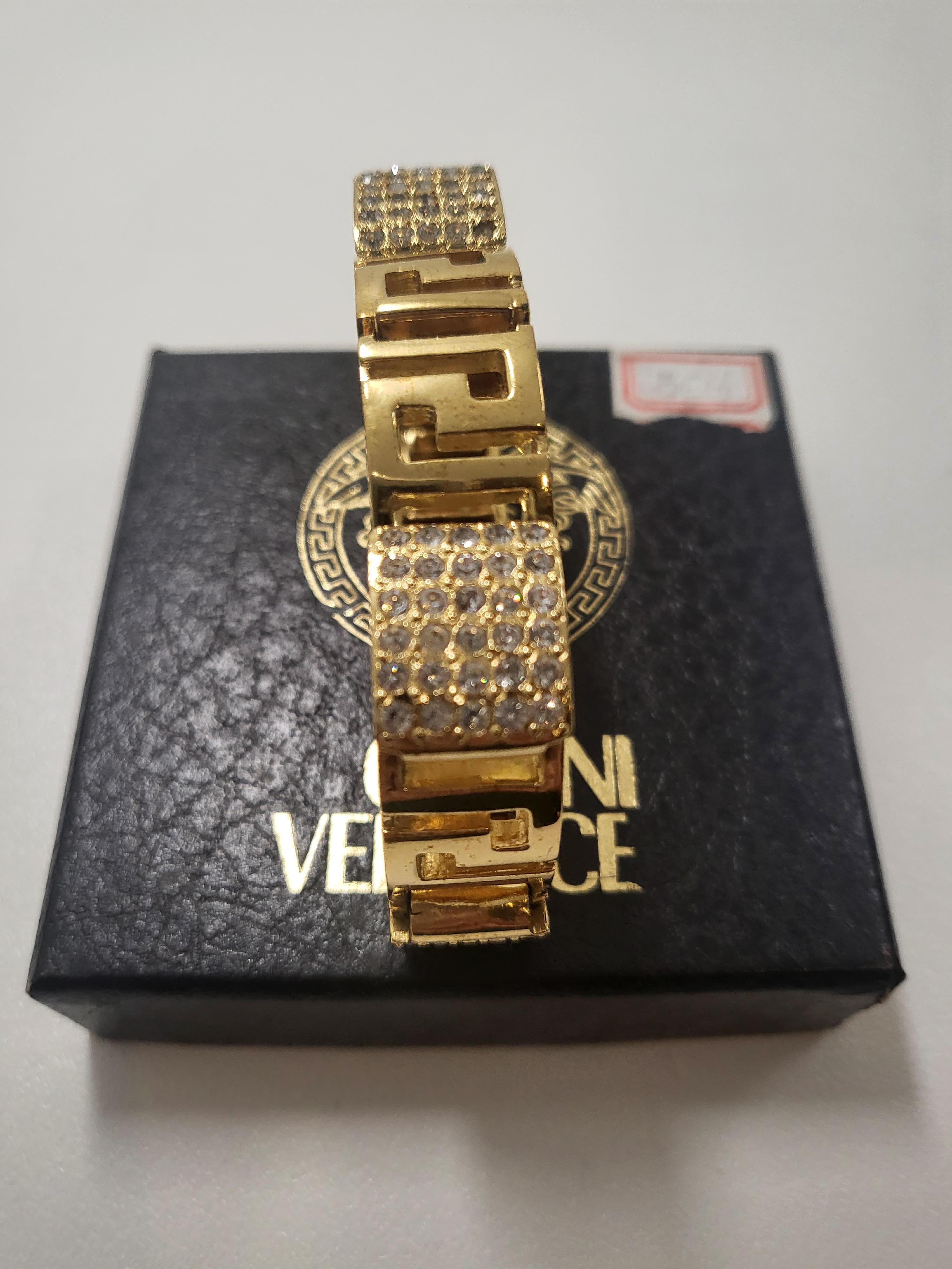 Adéntrate en el mundo del glamour vintage con la pulsera Gianni Versace Gold Rhinestones Greca Chunky Bracelet de los años 90, una obra maestra atemporal que encierra la opulencia y el estilo icónico de la época. Elaborada con meticulosa atención al