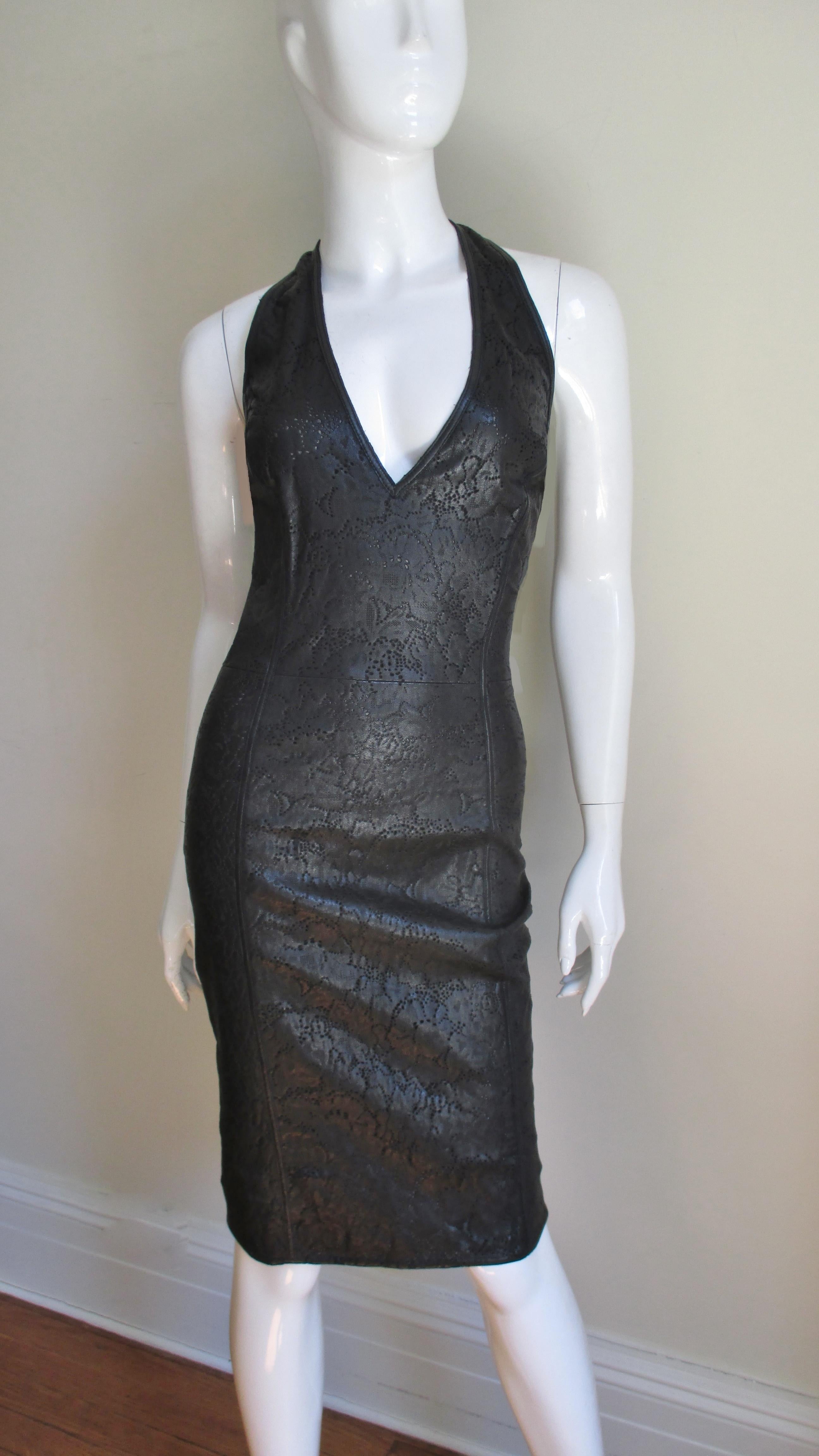 A fabulous laser cut black leather halter dress by Gianni Versace. It has a plunging neckline and low cut back accentuated with 2 fine leather straps crossing it. The leather is intricately laser cut in a pattern of tiny perforations and abstract