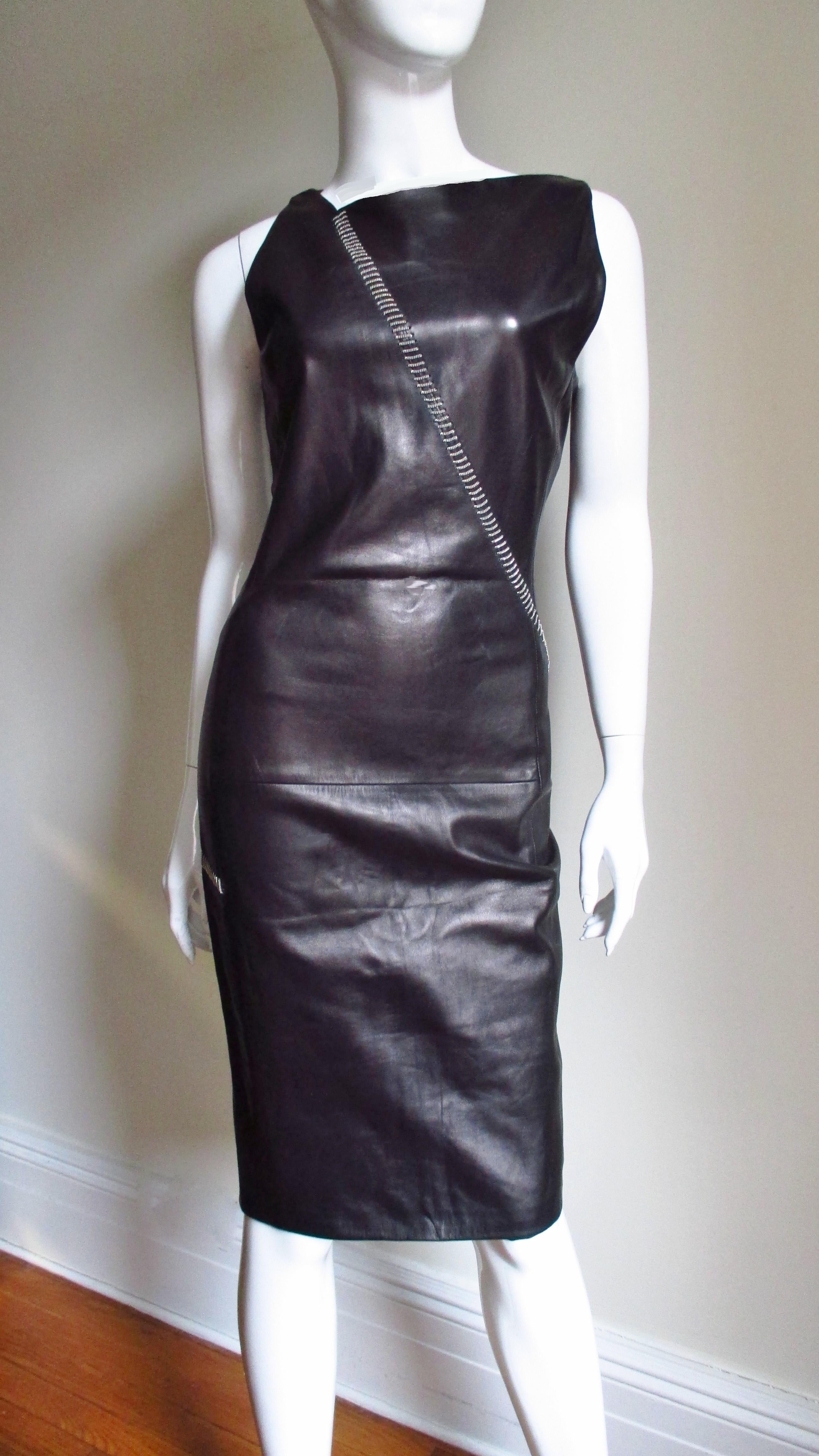A fabulous black leather dress from Gianni Versace.  It is fitted with an asymmetrical neckline with chain detail starting at one side wrapping around the dress across the hips in the back.  It is fully lined with a back zipper and a center back