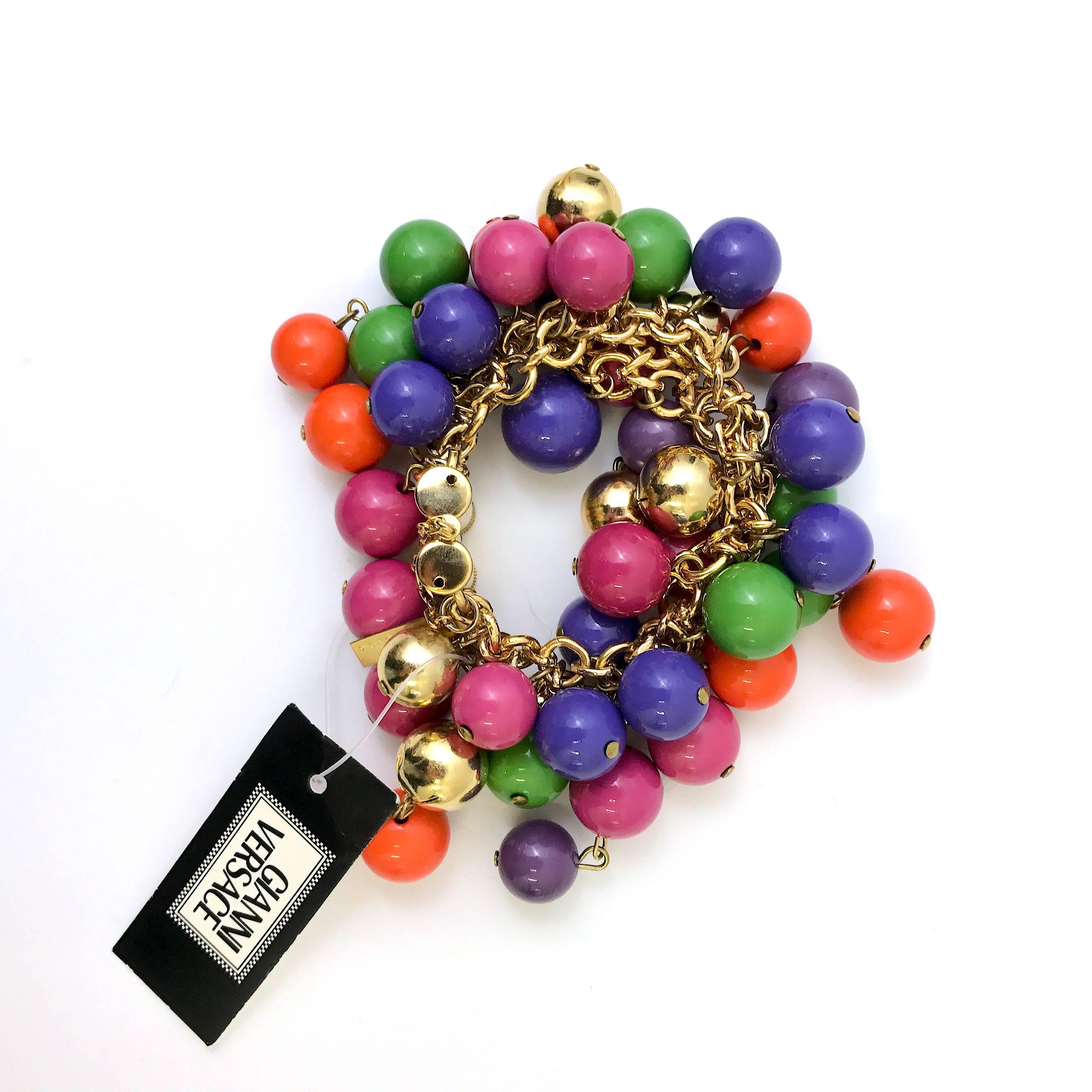 This bracelet by Gianni Versace is very rare with it's multicoloured cluster beaded design. It definitely is a collectors item for any Gianni Versace enthusiast. Features multi-bright colored round beads,which hang from a gilded gold tone metal