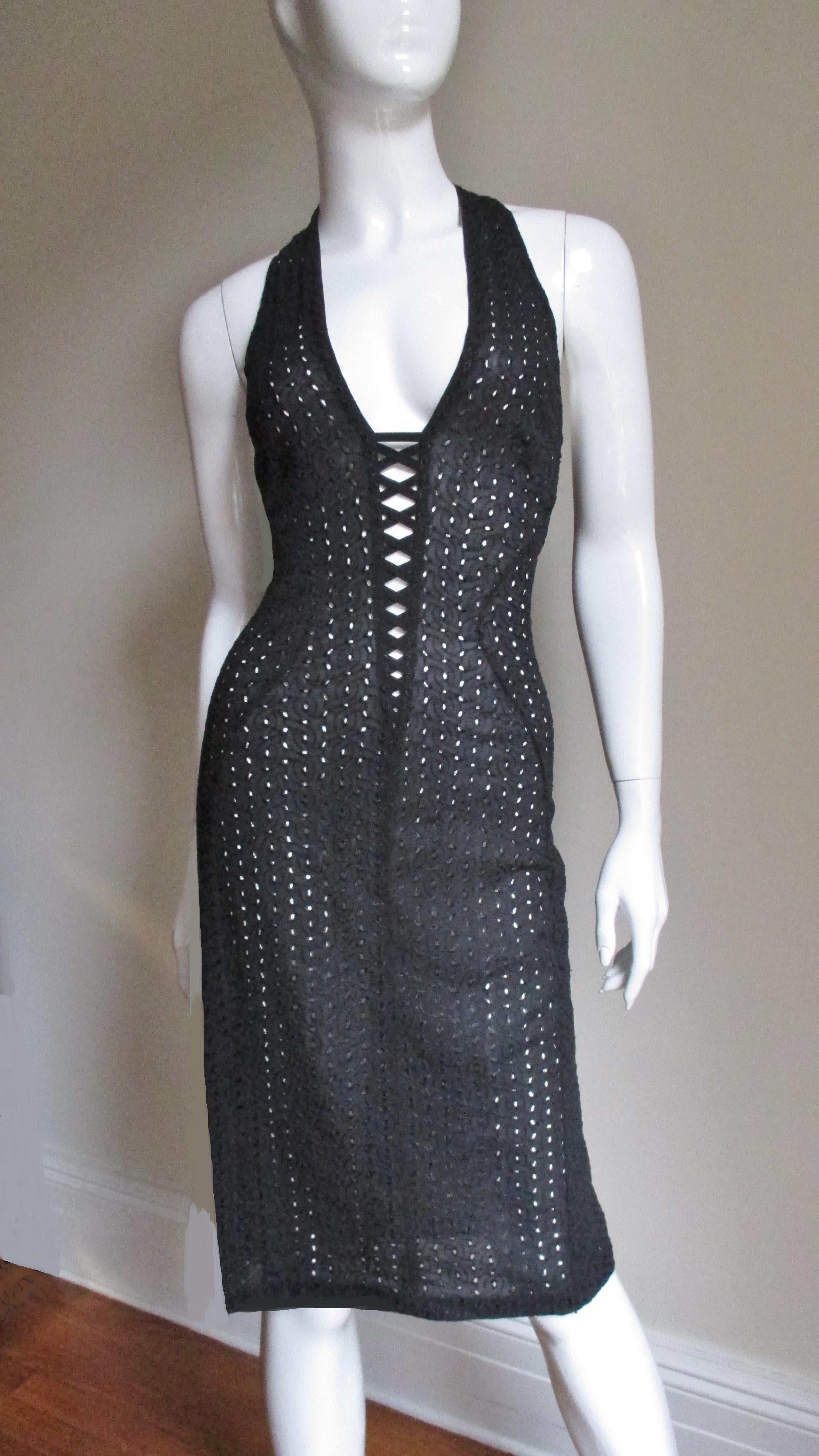 A fabulous bodycon dress in black perforated silk by Gianni Versace Couture.  It has a plunging neckline to the waist with lacing to the lower decolletage and straps crossing at the upper back.  The dress has flattering seaming cutting in at the