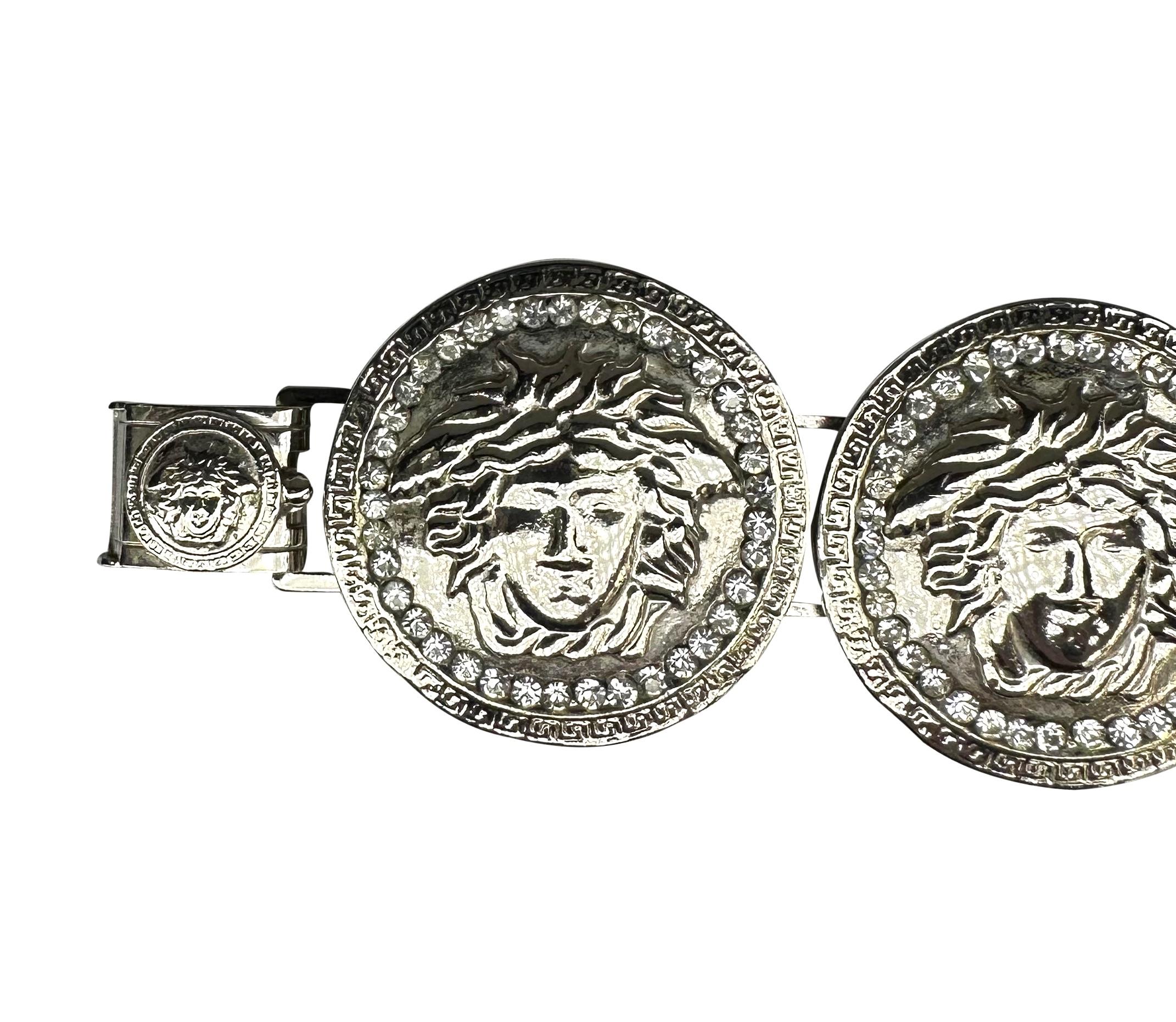 Questo bracciale Gianni Versace degli anni '90 presenta gli iconici medaglioni della Medusa ornati da strass con finitura argentata. Il design audace mostra quattro volti di Medusa, ciascuno circondato da una fila di strass scintillanti.

Misure