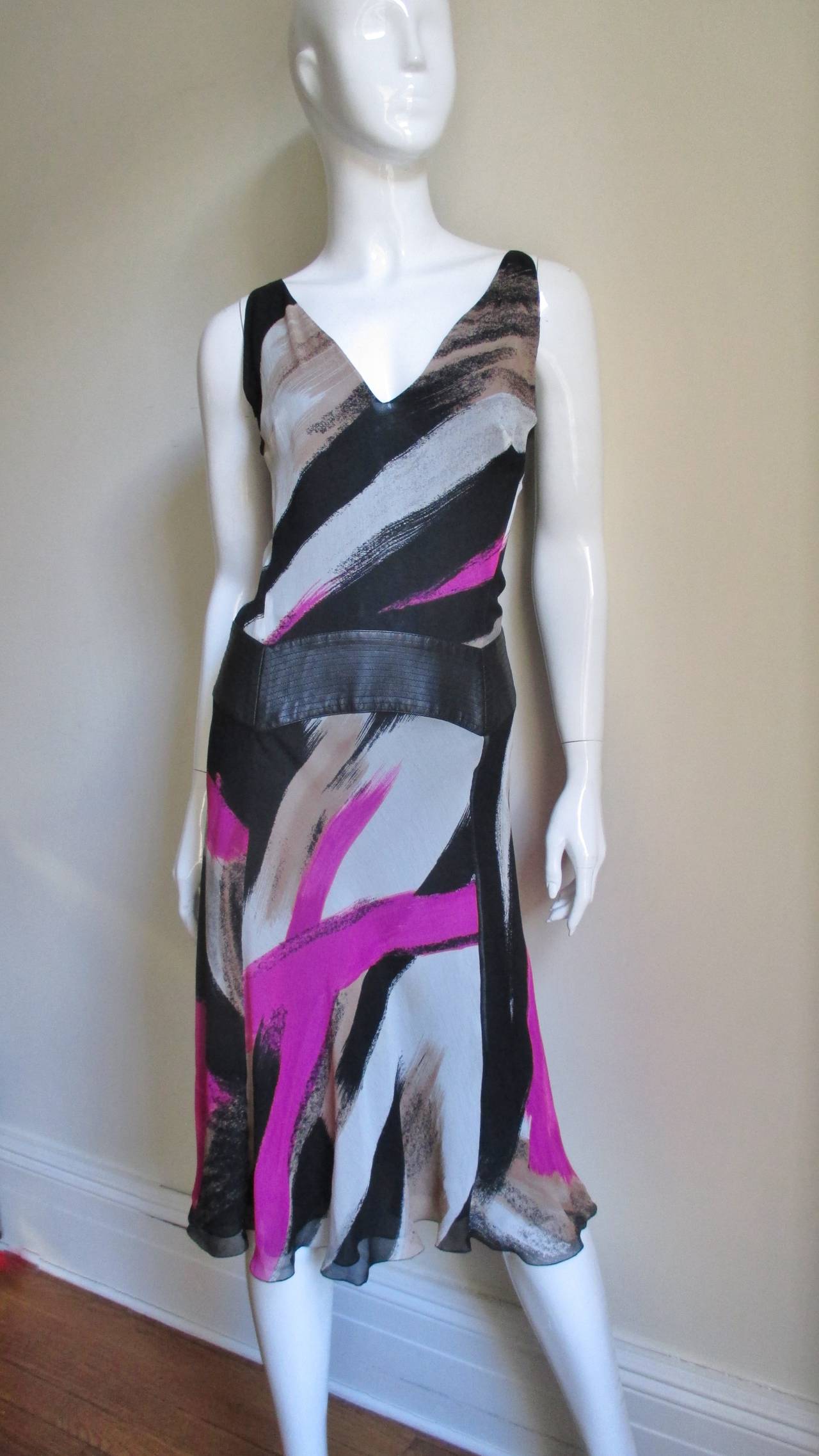 A beautiful silk dress from Gianni Versace in an abstract bright pink, taupe, black and white print.  It is sleeveless with a V neckline, a top stitched leather inset around the hips and a skirt flaring towards the hem. It has a side zipper and is