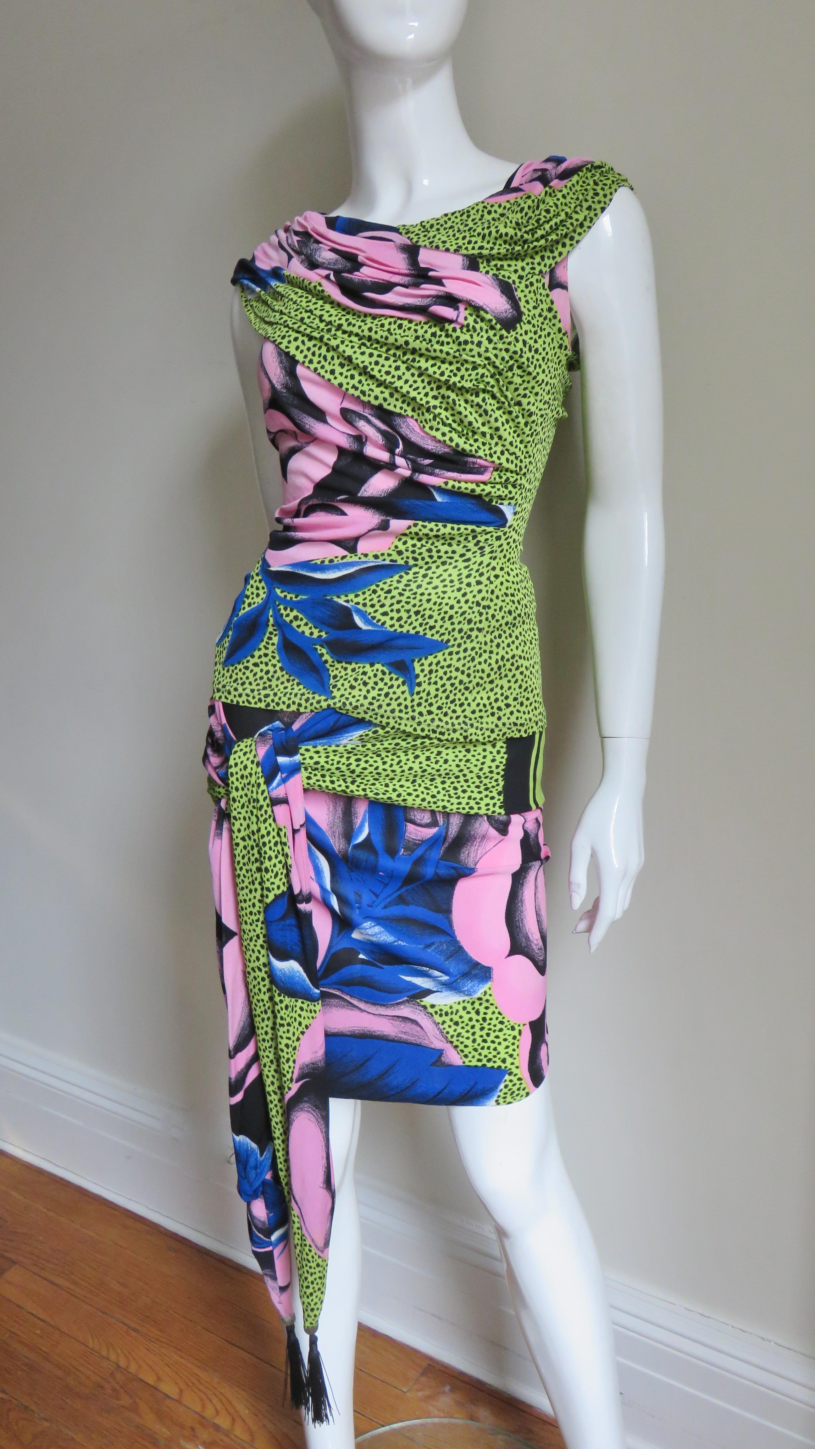 An fabulous jersey skirt and top set from an early collection of Gianni Versace in a bold pattern of pink flowers and blue leaves on a lime green background. The fitted top is ruched over the shoulders and diagonally across the front.  The skirt has