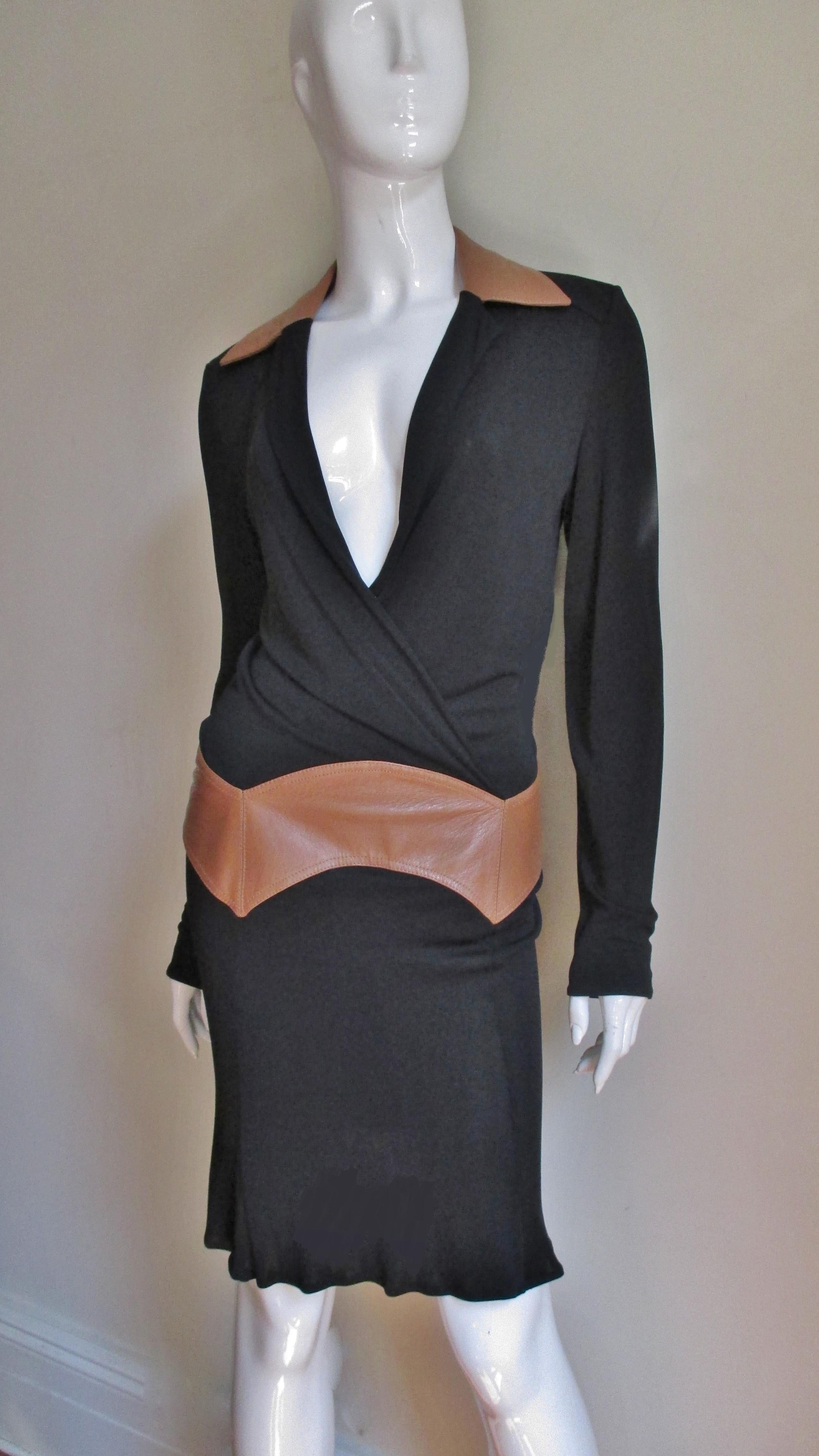 A fabulous black silk jersey dress from Gianni Versace Couture. The long sleeve bodice crosses in the front creating an adjustable neckline. It has a tan colored leather inset around the hips which narrows at the back and a matching leather collar.