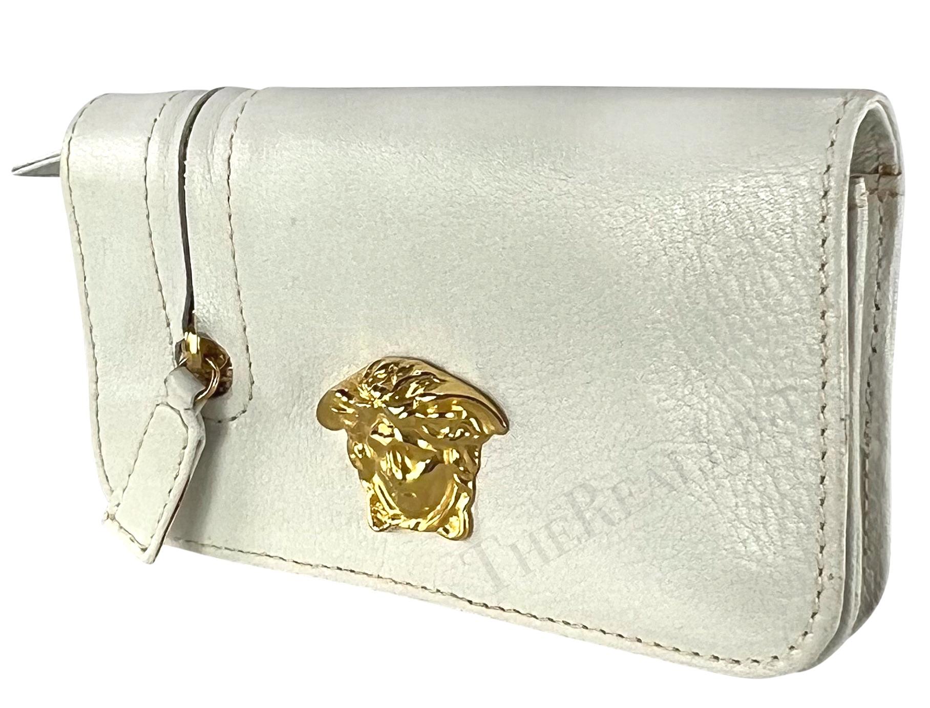 Gianni Versace designed this fabulous white leather Gianni Versace belt bag. From the 1990s, this white leather bag/wallet features a large gold-tone Medusa accent at the front, a zipper pocket at the exterior, a flap closure and is made complete