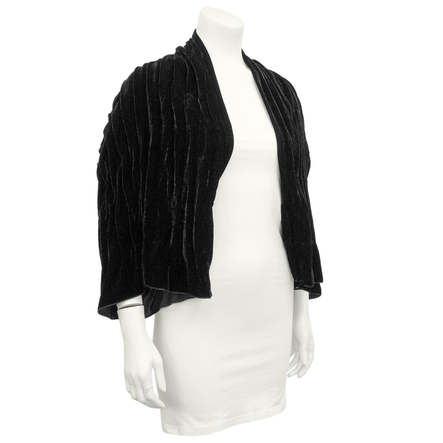 1990s Giorgio Armani black velvet bolero shrug. Designed to be worn open. Bracelet length sleeves. Velvet is folded and pleated vertically in the front and horizontally in the back. The pleating adds beautiful texture and allows light to hit the