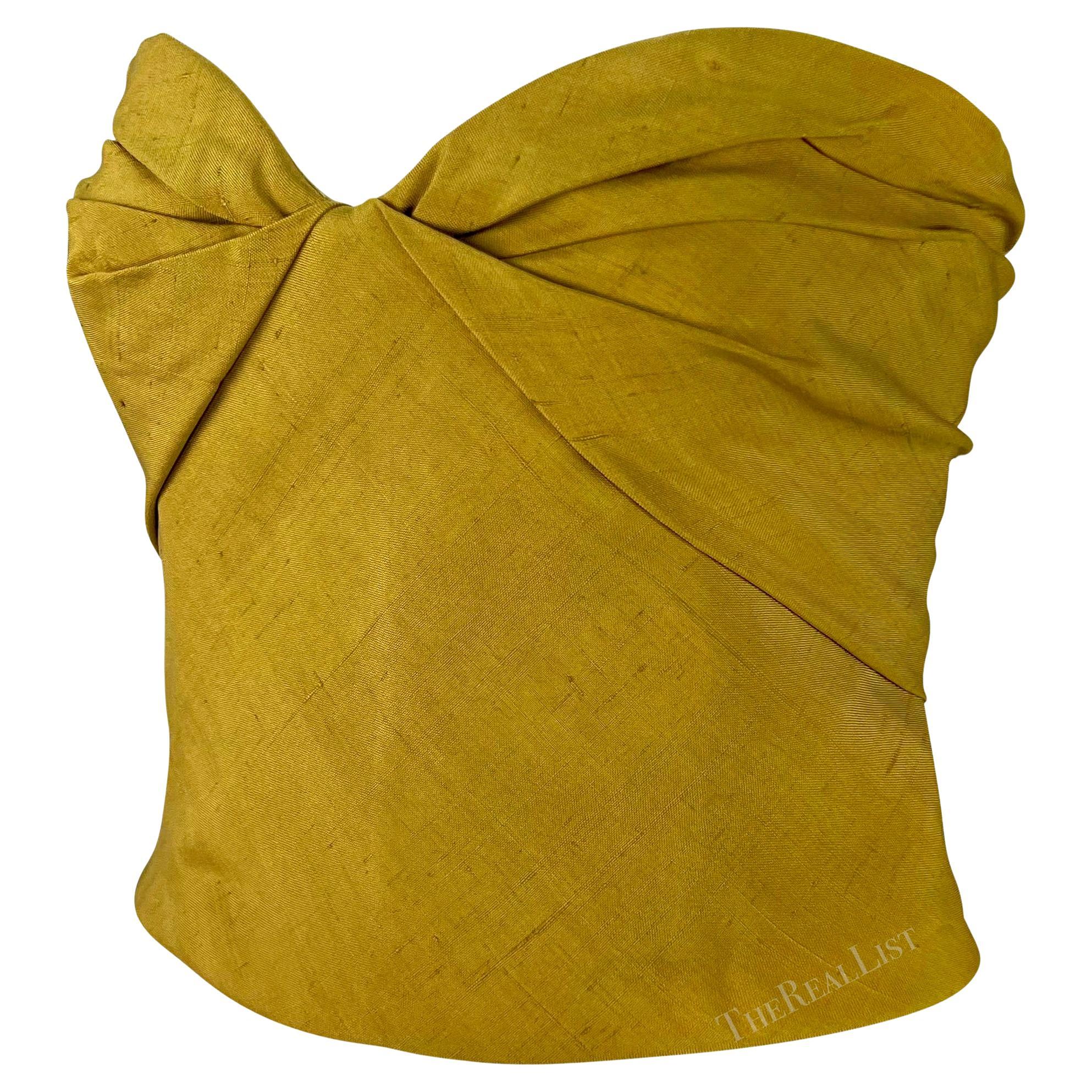 From the 1990s, this chic mustard silk Giorgio Armani strapless crop top features a sweetheart neckline with a twisted effect at the bust. This versatile vintage Giorgio Armani top is easily dressed up or down and is the perfect addition to any