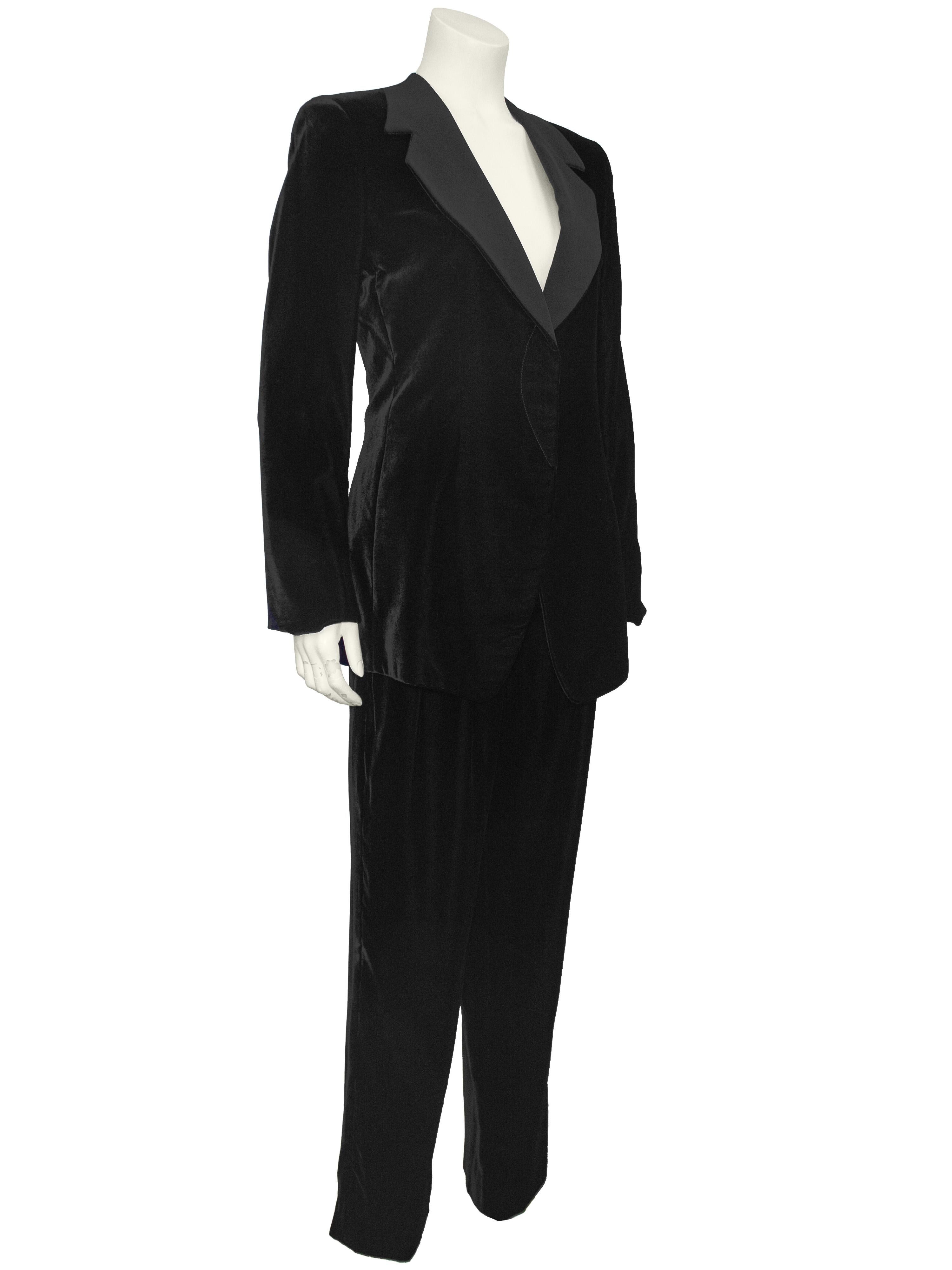 Tailleur pantalone in velluto nero Giorgio Armani dal taglio perfetto degli anni '90. L'abito è caratterizzato da una giacca da smoking con revers dentellato in raso di seta nero. Forma classica con abbottonatura per nascondere i bottoni e aderente