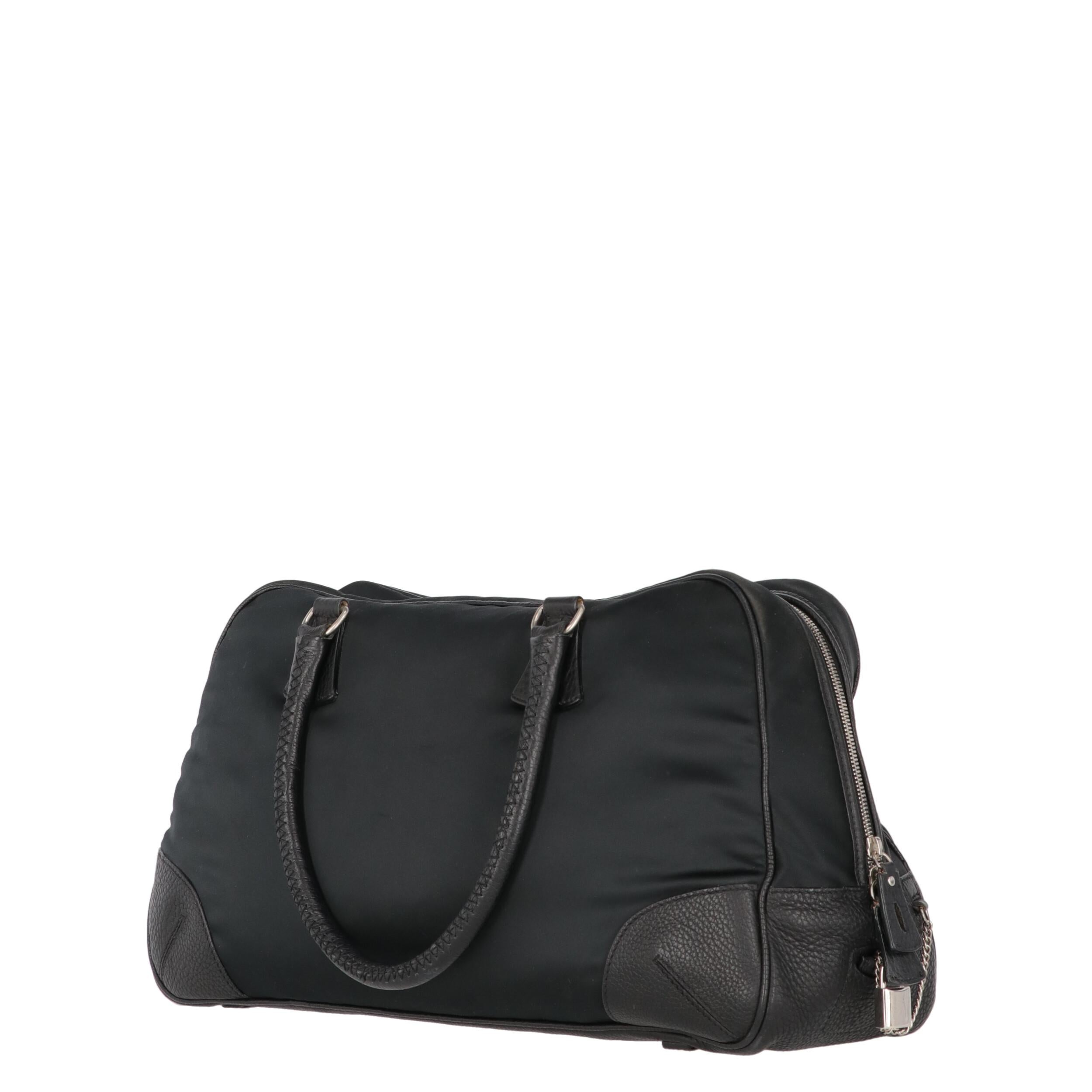 Giorgio Armani black nylon  travel bag with edges finished in leather. Two leather handles, two-way zip closure and lock with key.

The bag shows slight signs of wear on the corners and on the fabric, as shown in the pictures.
Years: 90s

Made in