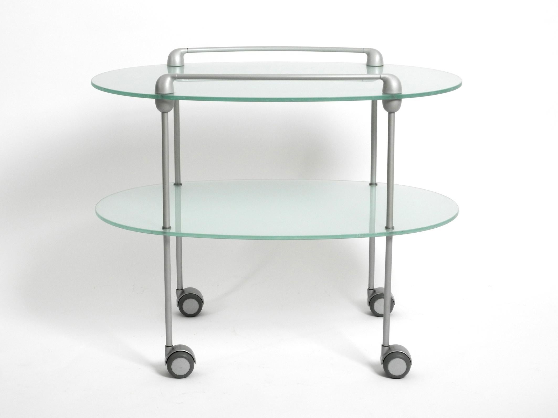 Very rare Minimalist glass serving trolley, model MYRIADES.
Designed by D'Orbino and Lomazzi in 1999 for Ligne Roset. Made in France.
Two oval heavy plates made of frosted glass with an aluminum frame on wheels.
Very good condition with very few