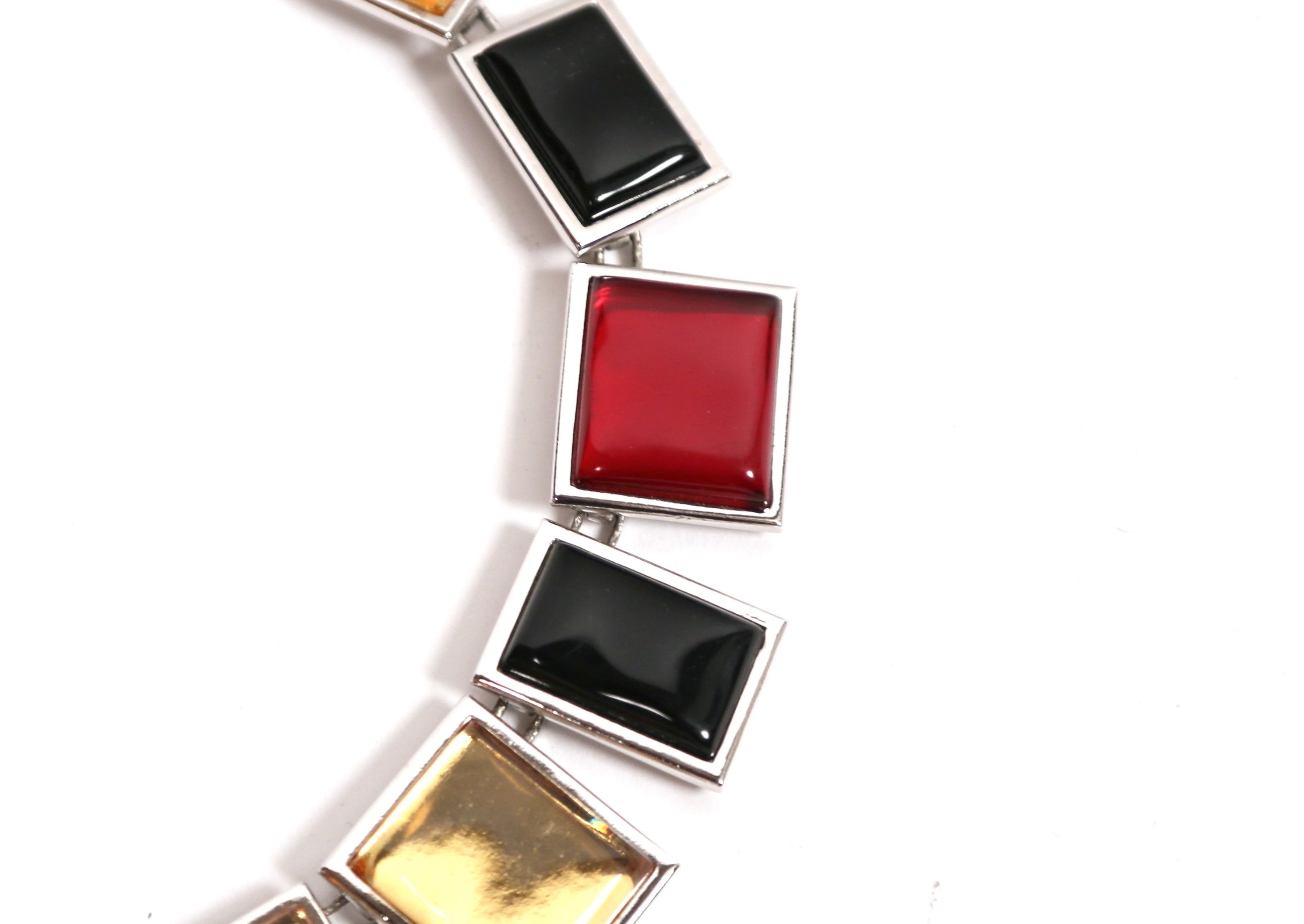 Questa collana numerata di Yves Saint Laurent degli anni '90 presenta un audace design di ispirazione cubista composto da grandi pannelli rettangolari in resina nei colori rosso intenso, oro e nero, ciascuno incastonato in metallo argentato. La