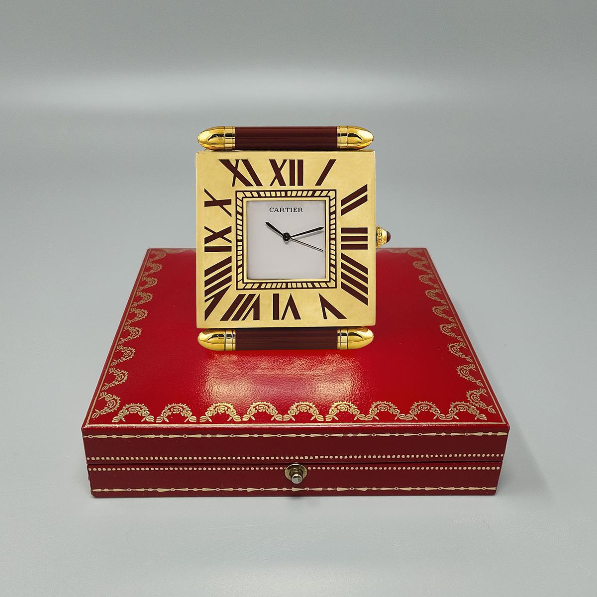1990s Gorgeous Cartier alarm clock pendulette with white dial in perfect condition, steel hands, roman hour markers on gold-plated frame.  Made in Swiss.
Quartz movement. Clock case numbered 890904181. With original case, lined with red leather. It