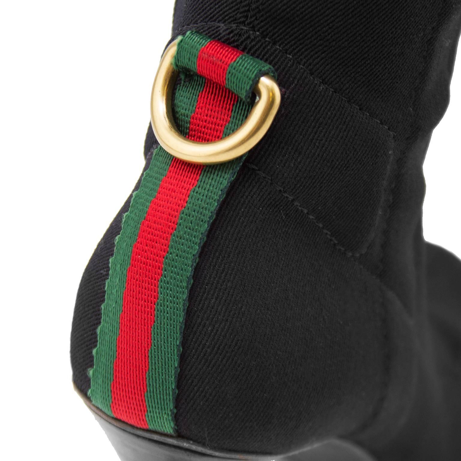 1990s Gucci black spandex knee high boots. Tonal black top stitching throughout. Classic Gucci green and red ribbon detail at heels with gold tone D ring. Black leather trim at top. Zipper at interior sides. 3