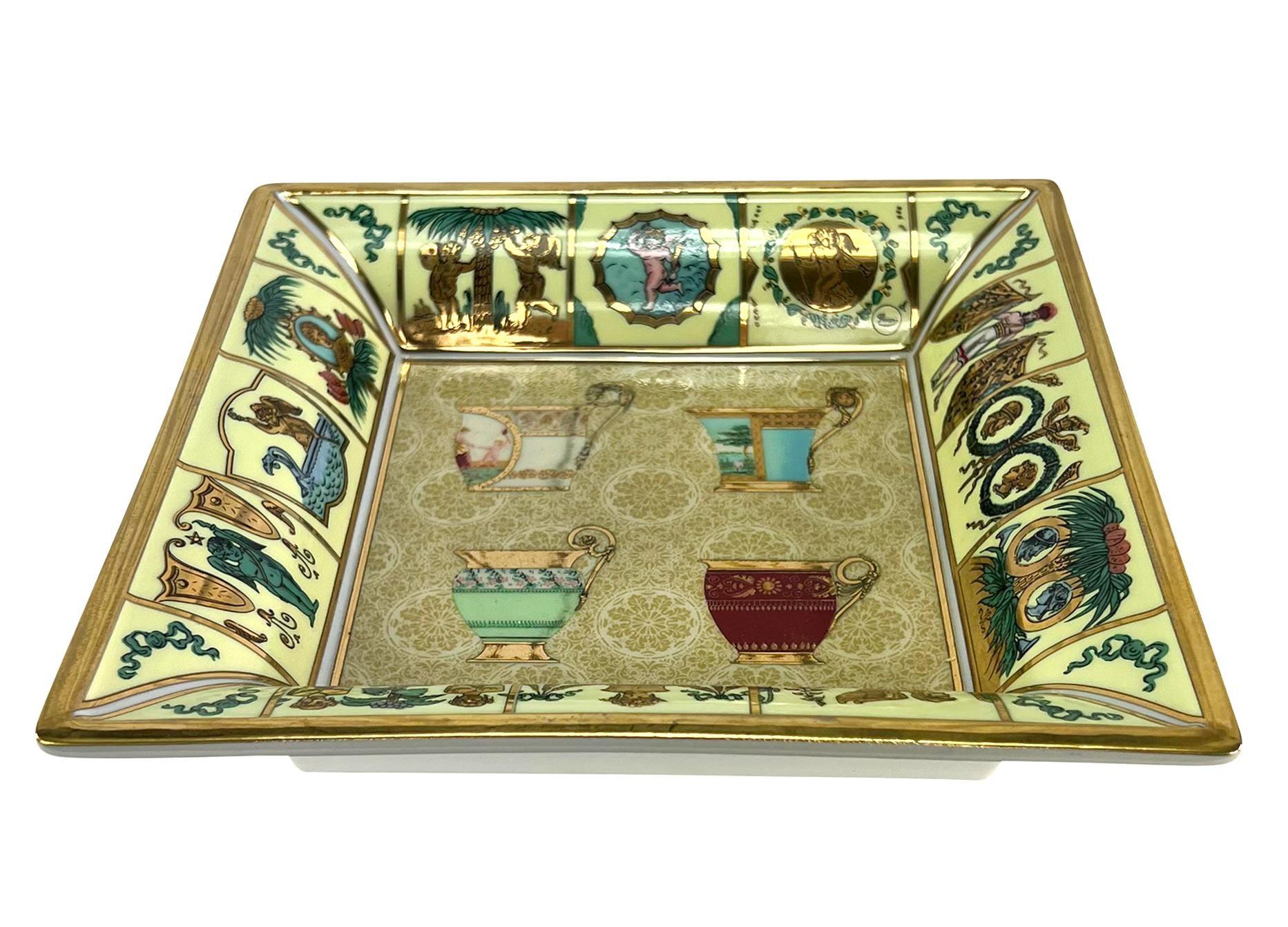 From the 1990s, this glamorous guilded Gucci dish can be a trinket, key, or ashtray. This square tray features gold gilding throughout and boasts a demitasse cup motif. 

Length: 7.5
