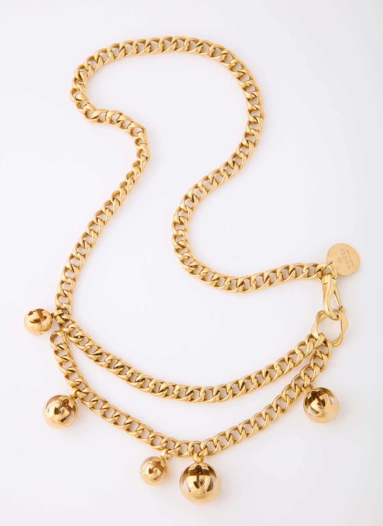One Ladies 18kt Yellow Gold Double Layer Link Necklace,Exhibiting An Unusual 18kt Watch Chain Style Clasp For Easy Wear.Necklace Is Designed With Five Gucci Signature Design Cow Bell Motif Embellishments.Signed Gucci, Circa 1990's.
