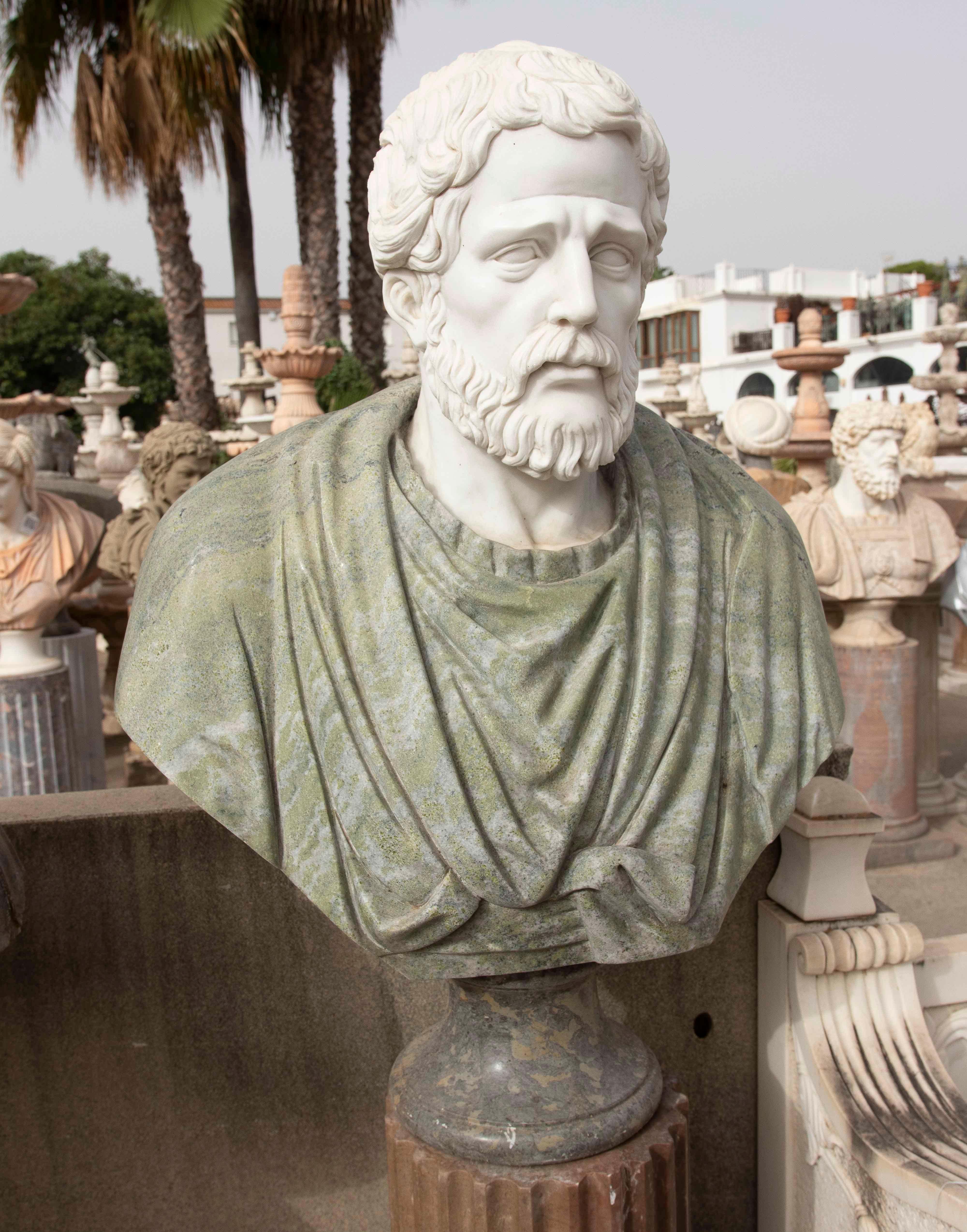 Un elegante busto in marmo classico scolpito a mano, che combina il bianco puro del volto con un mantello in marmo verde venato, creando un contrasto visivamente ricco. L'opera raffigura una figura maschile barbuta con un'espressione solenne e