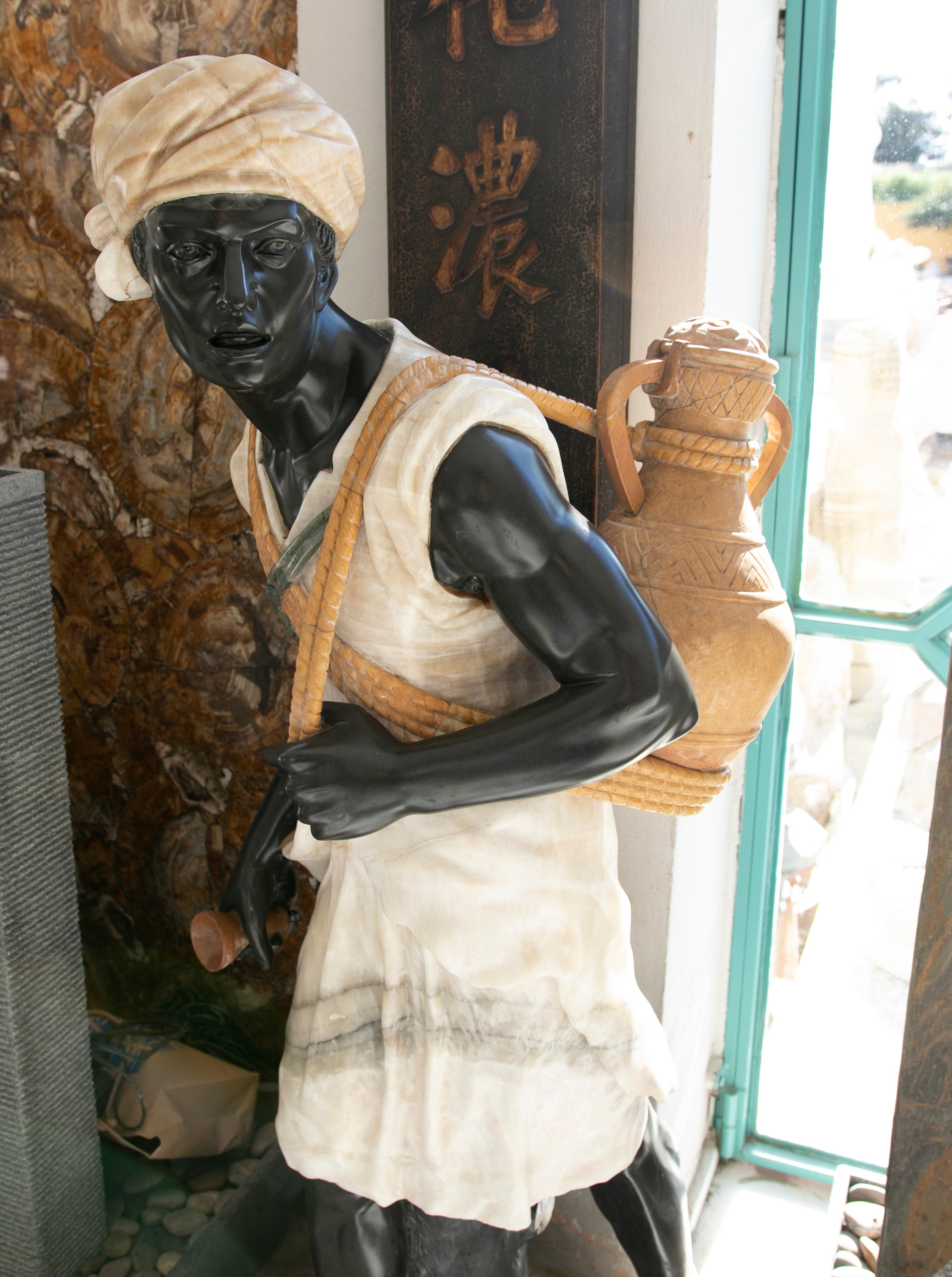 1990s Hand carved onyx and marble sculpture of a water-carrier character.