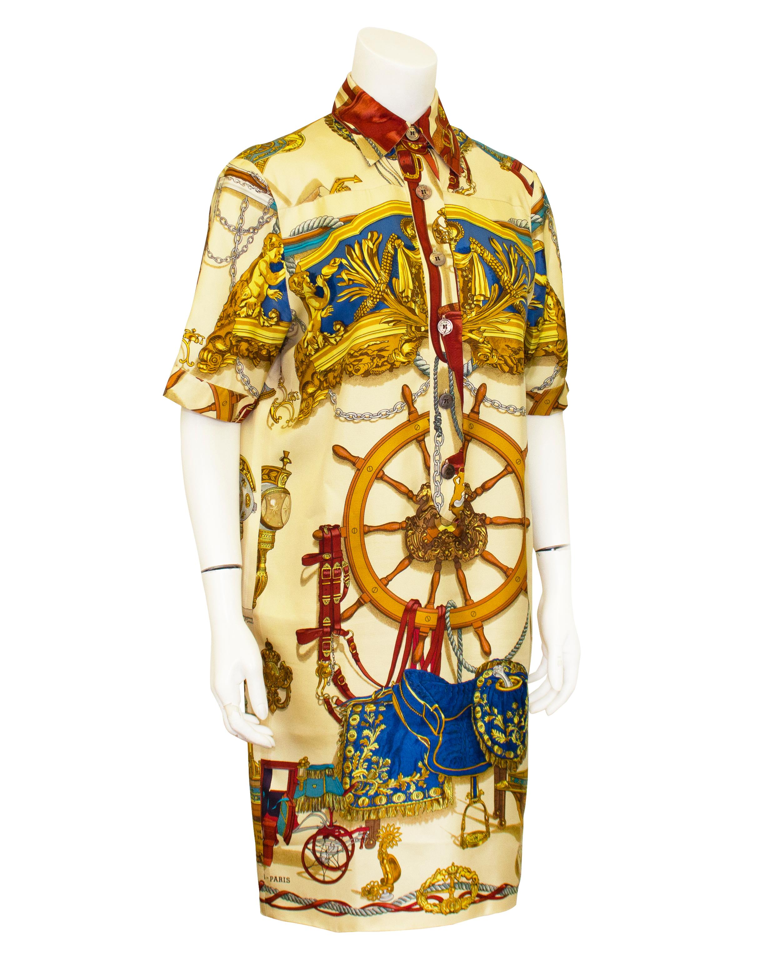 Schönes Hermes-Kleid aus den 1990er Jahren. 100% Seide mit klassischem Hermes-Print mit kastanienbraunen, königsblauen, goldenen, silbernen und braunen Motiven wie Pferdezaumzeug, Ankern, Schiffssteuerrädern, Pferdekutschen und verzierten