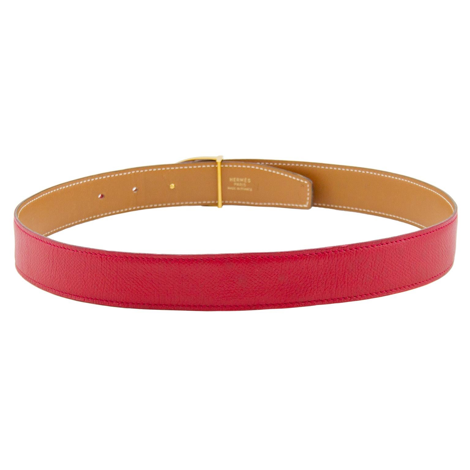 Stunning Hermes belt from 1990, as indicated by the blind stamp of a T in a circle. Rich red rigid leather with tonal exterior stitching and supple tan leather reverse with contrasting white top stitching. Gold tone stirrup buckle. Interior gold