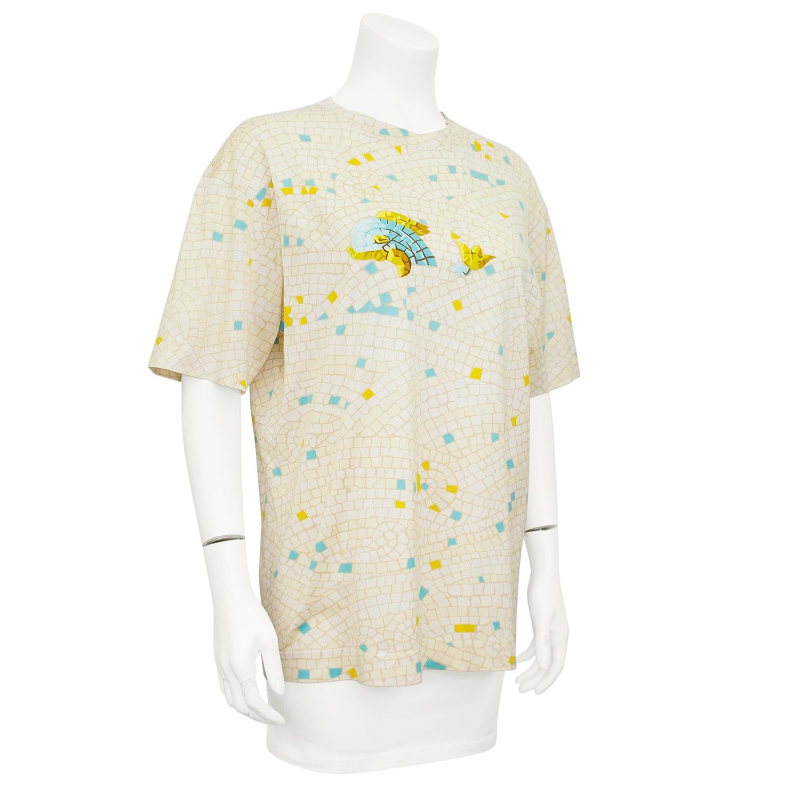 Silk cotton blend Hermes t-shirt from the 1990s. Cream and beige all over mosaic tile print with accent yellow and turquoise tiles. Front features a turquoise and gold mosaic tile whale. Crew neckline and short sleeves. Tonal top stitching.