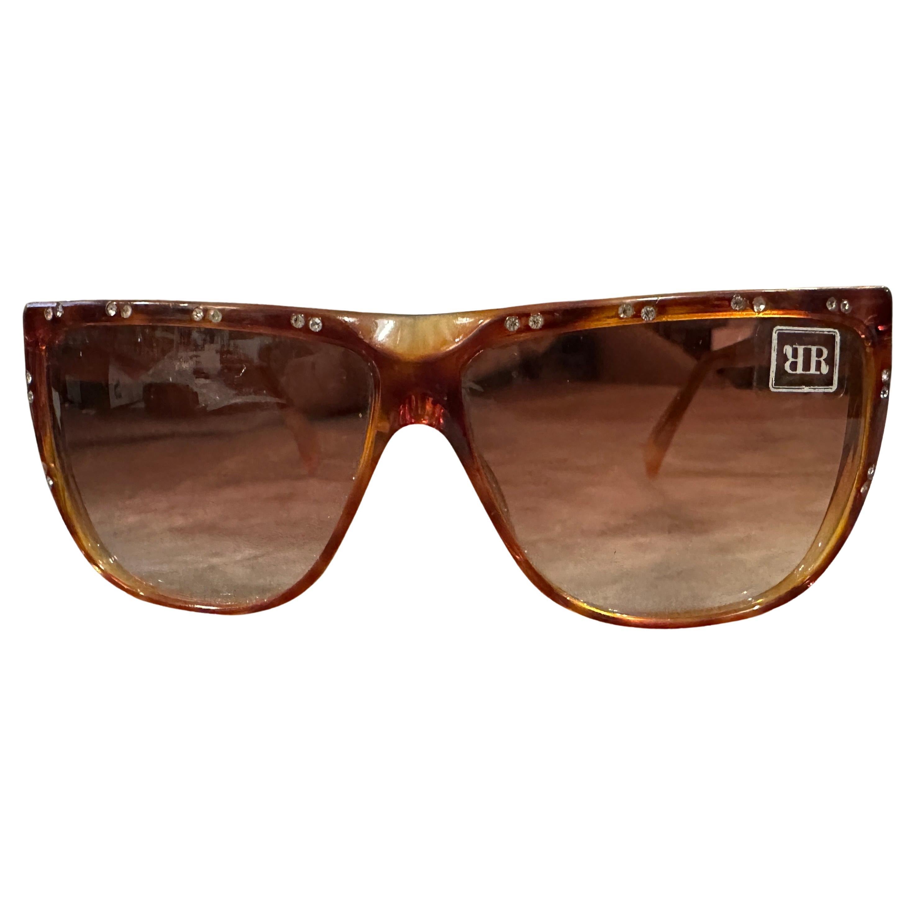 Vintage 1990s Raffaella Curiel Braun Acetat & Jewell Sonnenbrille
Diese authentische Vintage-Sonnenbrille der bekannten Designerin Raffaella Curiel aus den 1990er Jahren ist eine perfekte Mischung aus Raffinesse und Retro-Chic.
Das Gestell ist aus