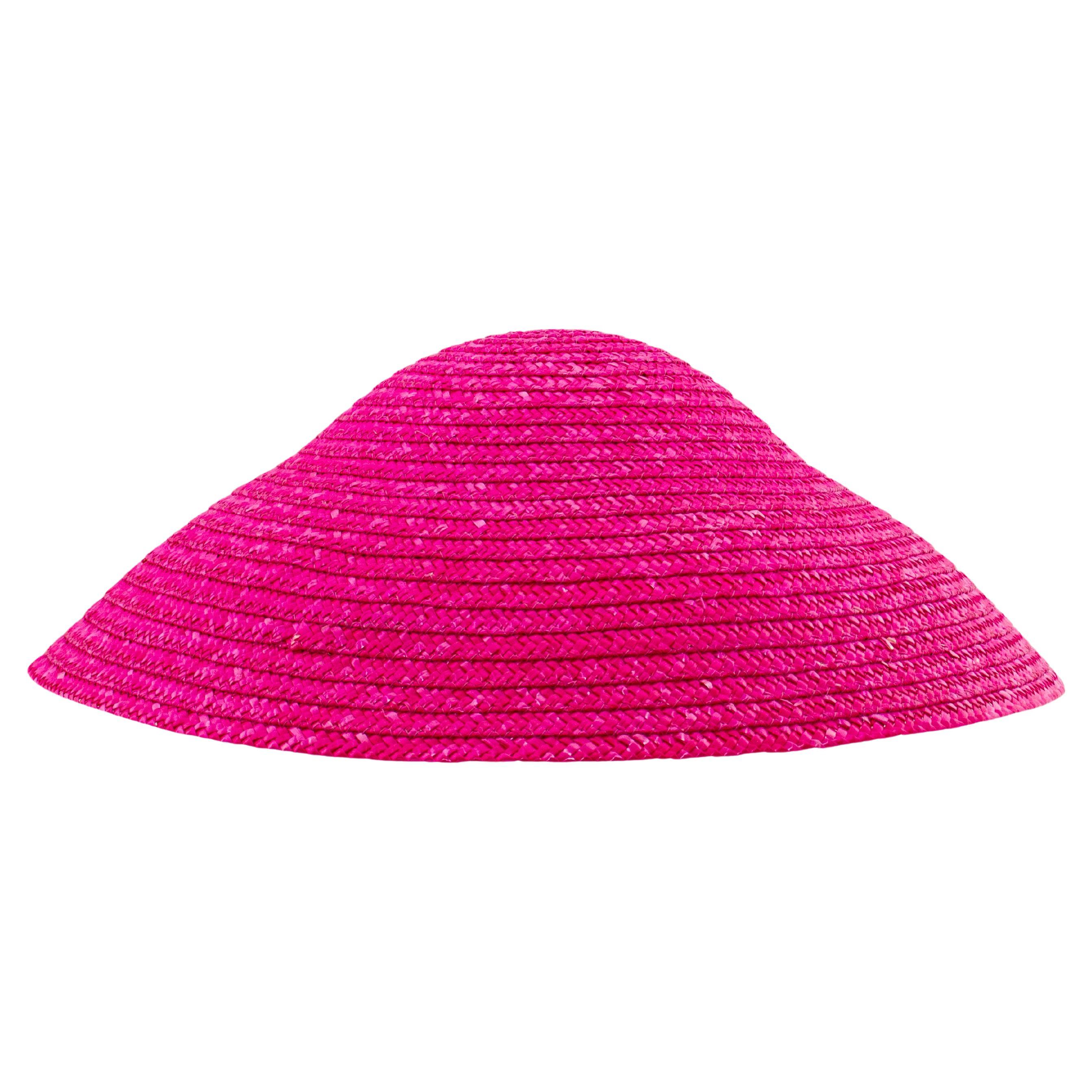 Make a bold statement under the sun with this vivid fuchsia straw hat from Canadian department store Holt Renfrew. Featuring a dramatic conical silhouette and a wide, angular brim, this eye-catching piece channels both vintage charm and avant-garde