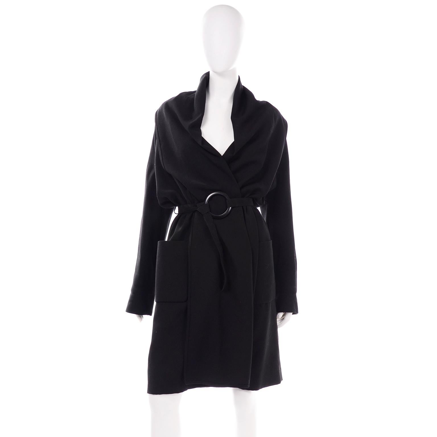 This is a beautiful black wool wrap coat by Isaac Mizrahi, with an oversized wide shawl collar. It wraps in front and secures with a thin wool belt that ties around a large circular buckle. This is a lighter weight wool, and would make an excellent
