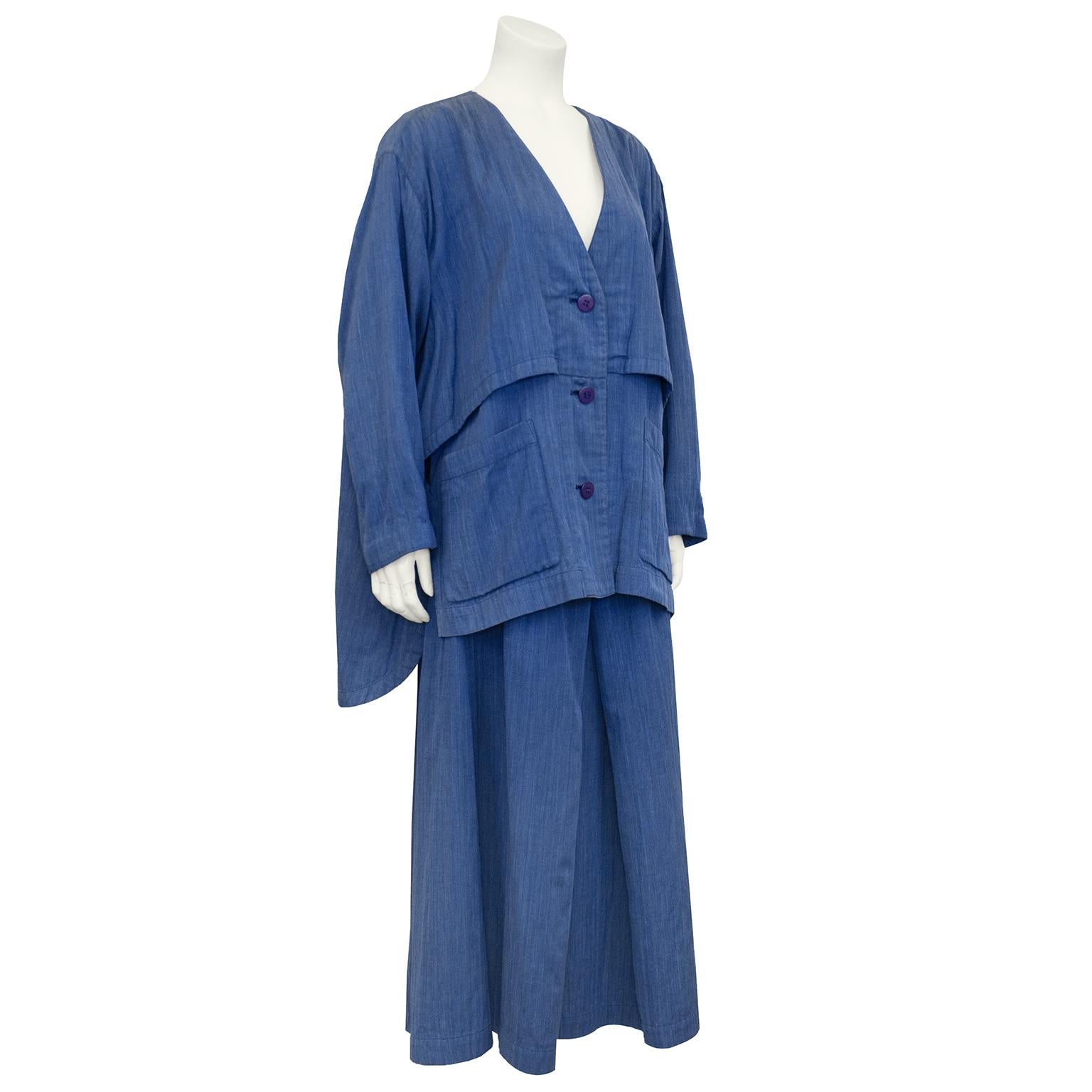 1990s Issey Miyake Permanente blue cotton that looks like a soft chambray denim oversized jacket and skirt ensemble. Jacket features a deep v neckline, large blue plastic buttons and large patch pockets. Jacket is A-line shape and longer in the