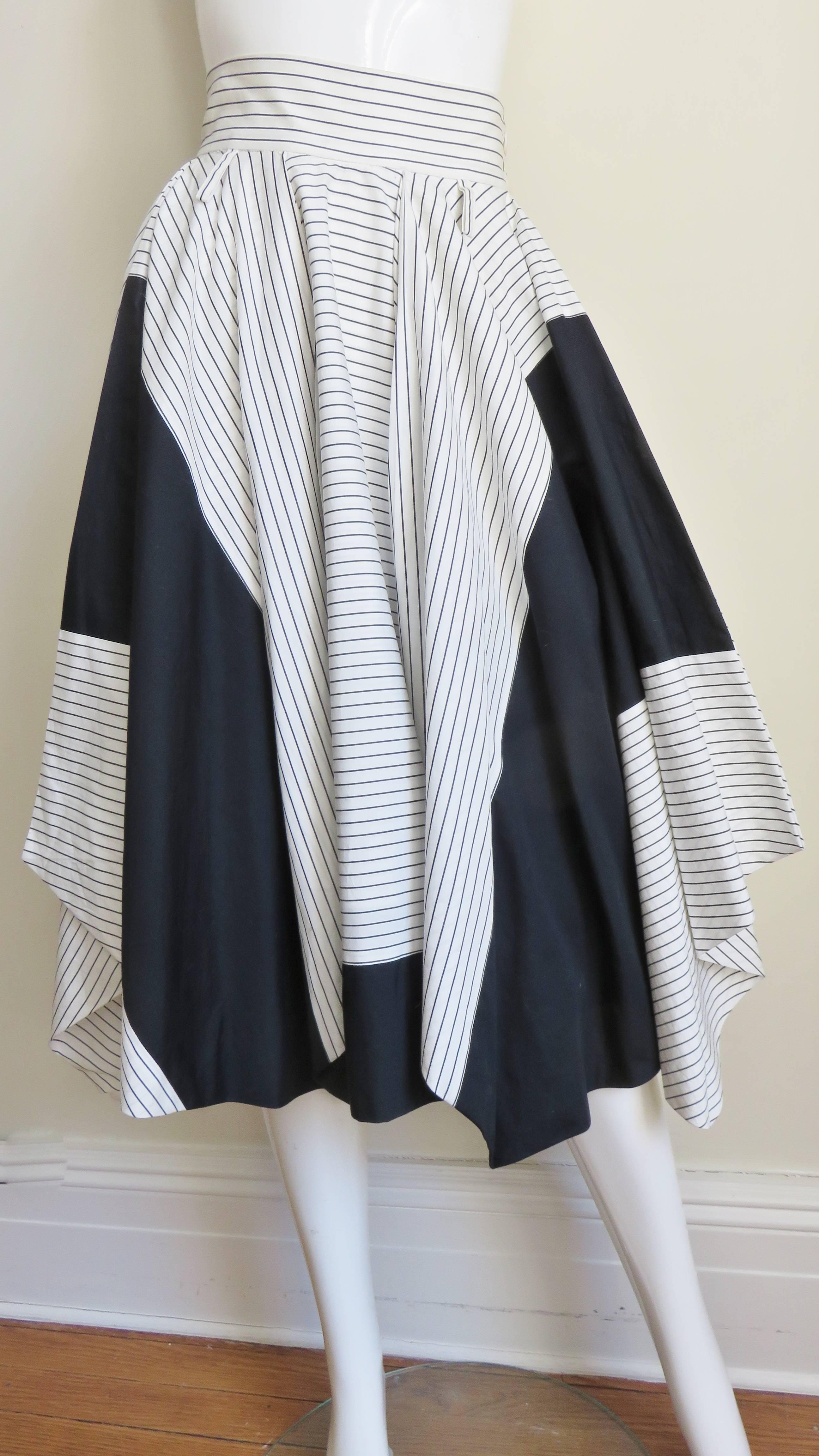 A fabulous black and white with black stripes cotton skirt from Issey Miyake.  It has a waistband and black inset panels in the white striped portion of the full skirt. It buttons at the side waist, has side seam pockets and is fully lined.   
Fits
