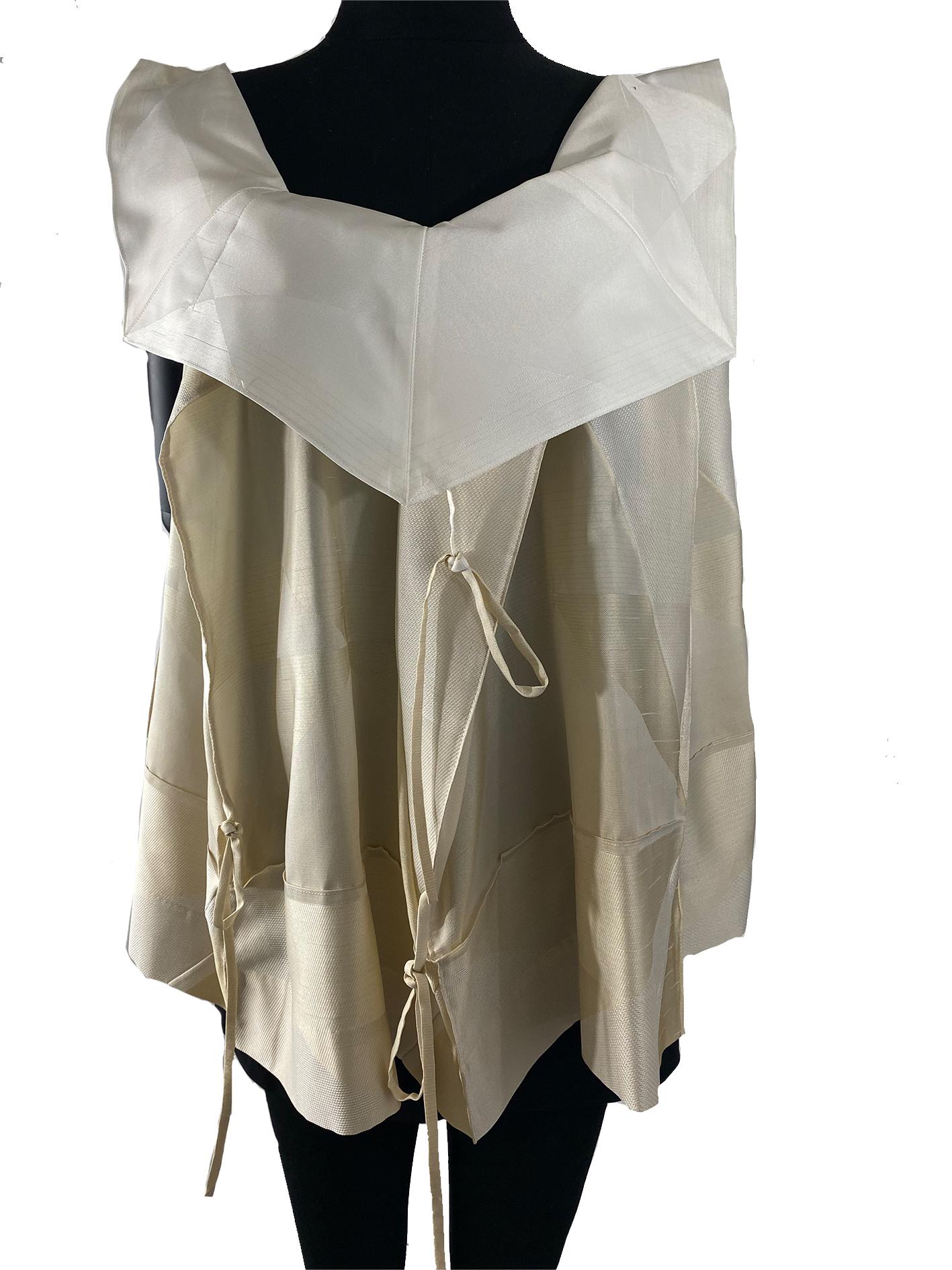 A late 1990’s Issey Miyake unstructured top of oatmeal, cream and off-white silk mixture damask, featuring an angular neckline with complementing ivory bib collar, and cut-away armholes, finished with decorative ties throughout. This item carries