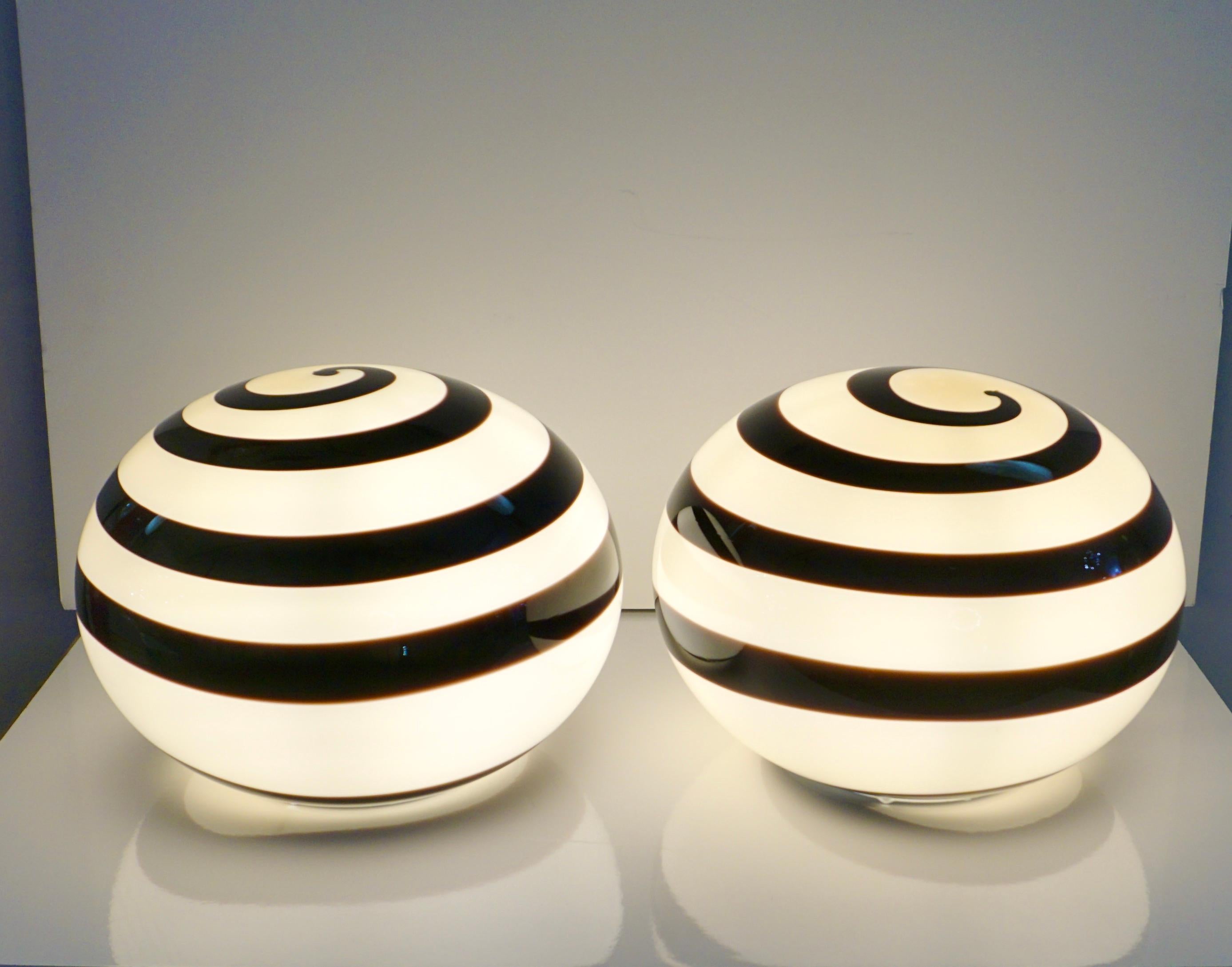 Do you miss the 1970s Design Style? So these are for you! A minimalist pair of late 20th Century Italian blown glass lamps, of simple oval shape with a geometric swirl pattern of overlaid glass spiraling black Murrina, the black and cream white